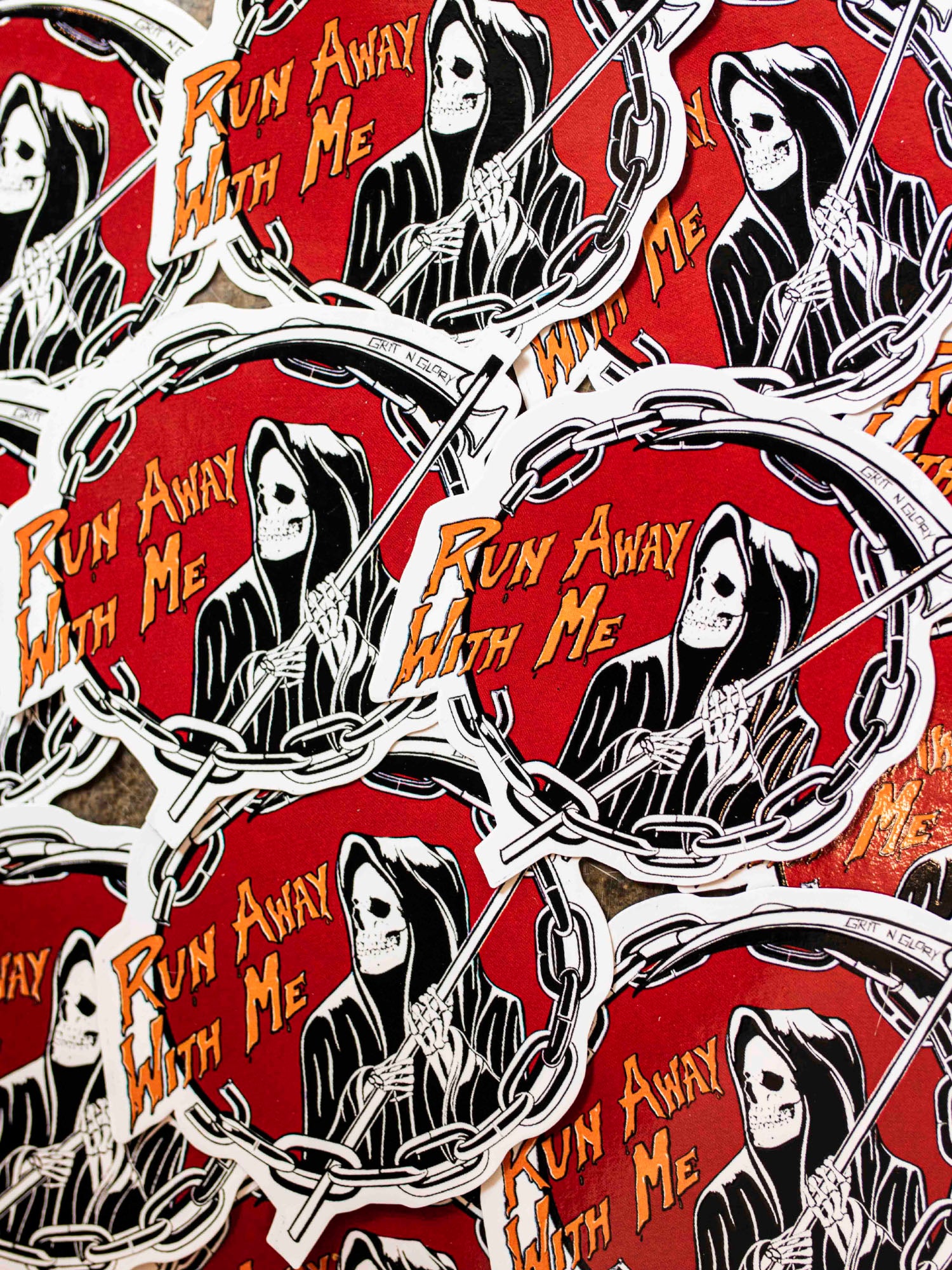 Die cut vinyl stickers with a black and white reaper design in a red circle