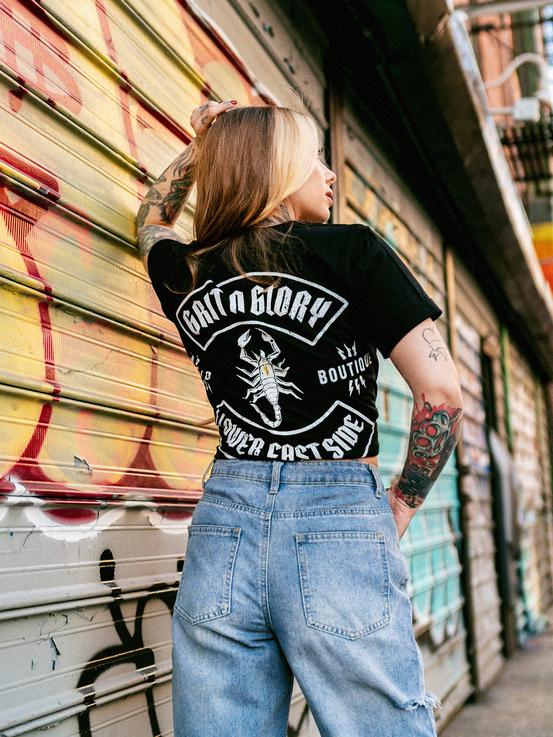 Megan Massacre wearing a black, short-sleeved T-shirt with a scorpion graphic on the back and the text 'Grit N Glory'.