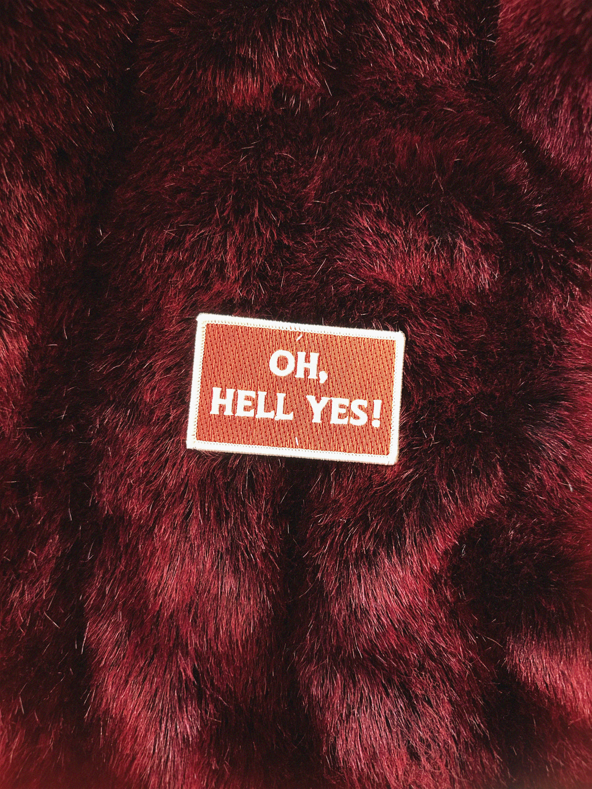 Red fluffy blanket with a patch saying 'OH, HELL YES!' 