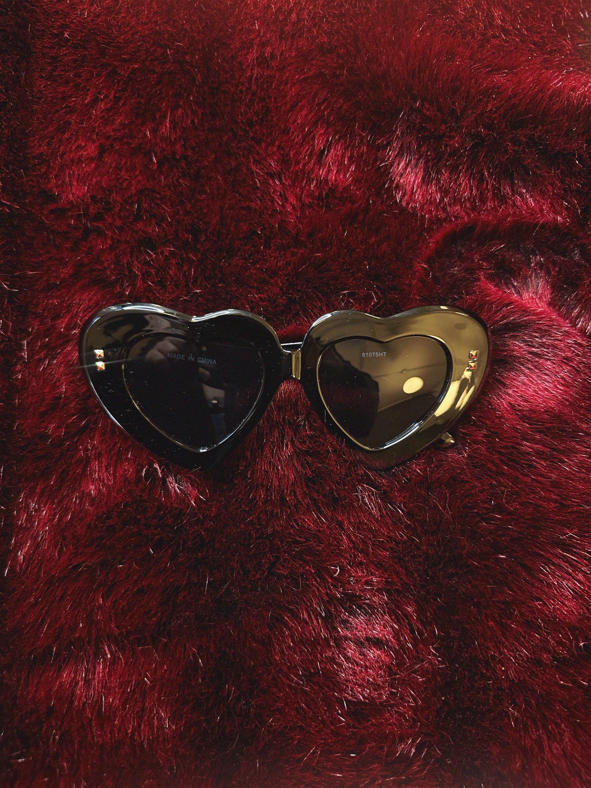 Pink heart-shaped sunglasses on a red furry surface