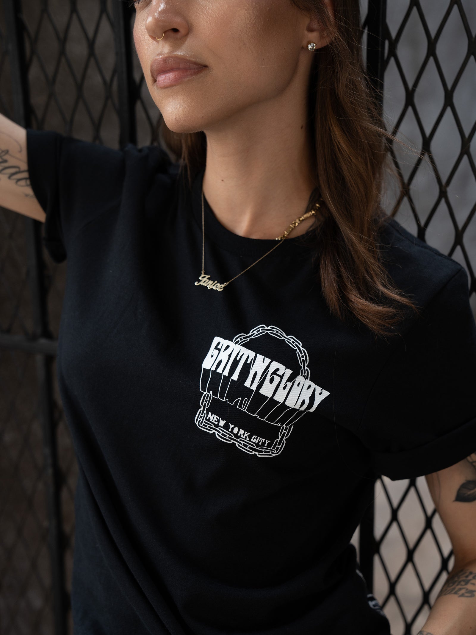 close up of front graphic on black t-shirt. Graphic reads "Grit N Glory New York City" within a chain border