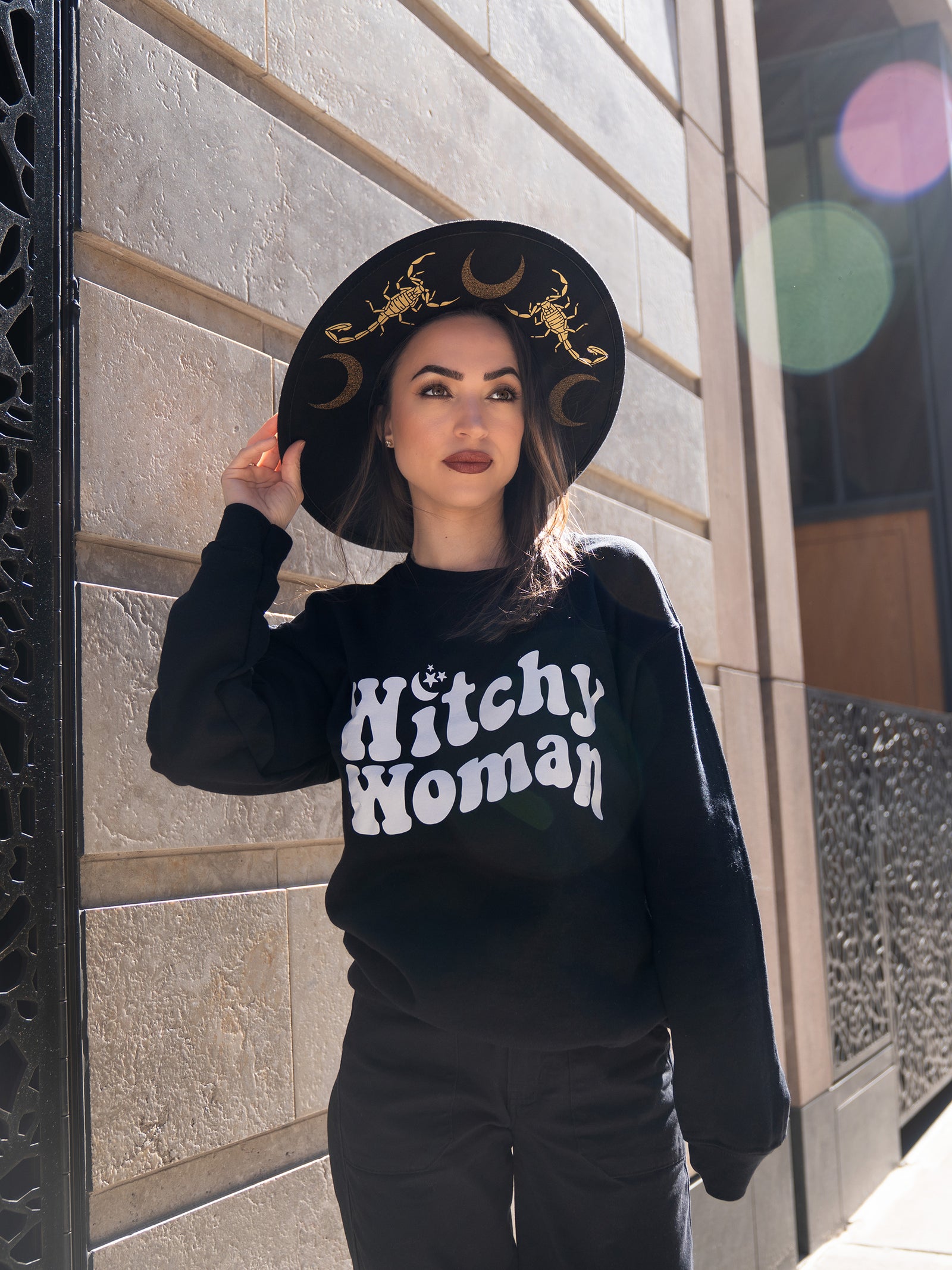 Janice Danger wearing the Witchy Woman black crewneck featuring a 70's style Witchy Woman graphic. 