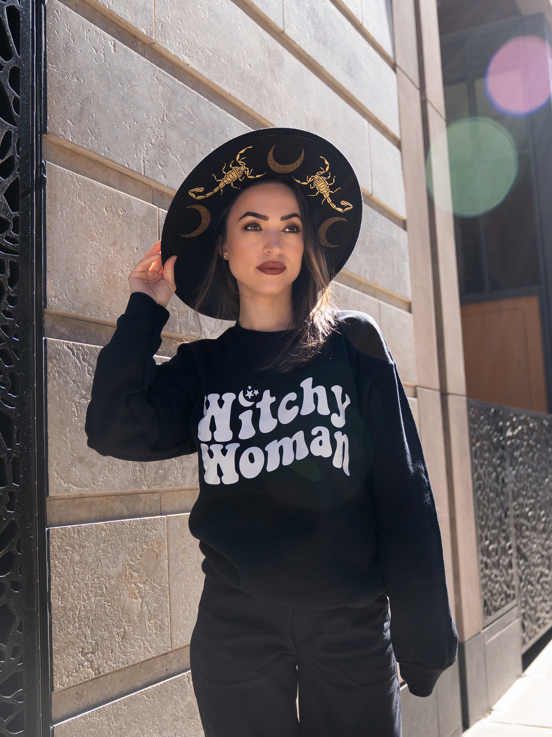 Janice Danger wearing the Witchy Woman black crewneck featuring a 70's style Witchy Woman graphic. 