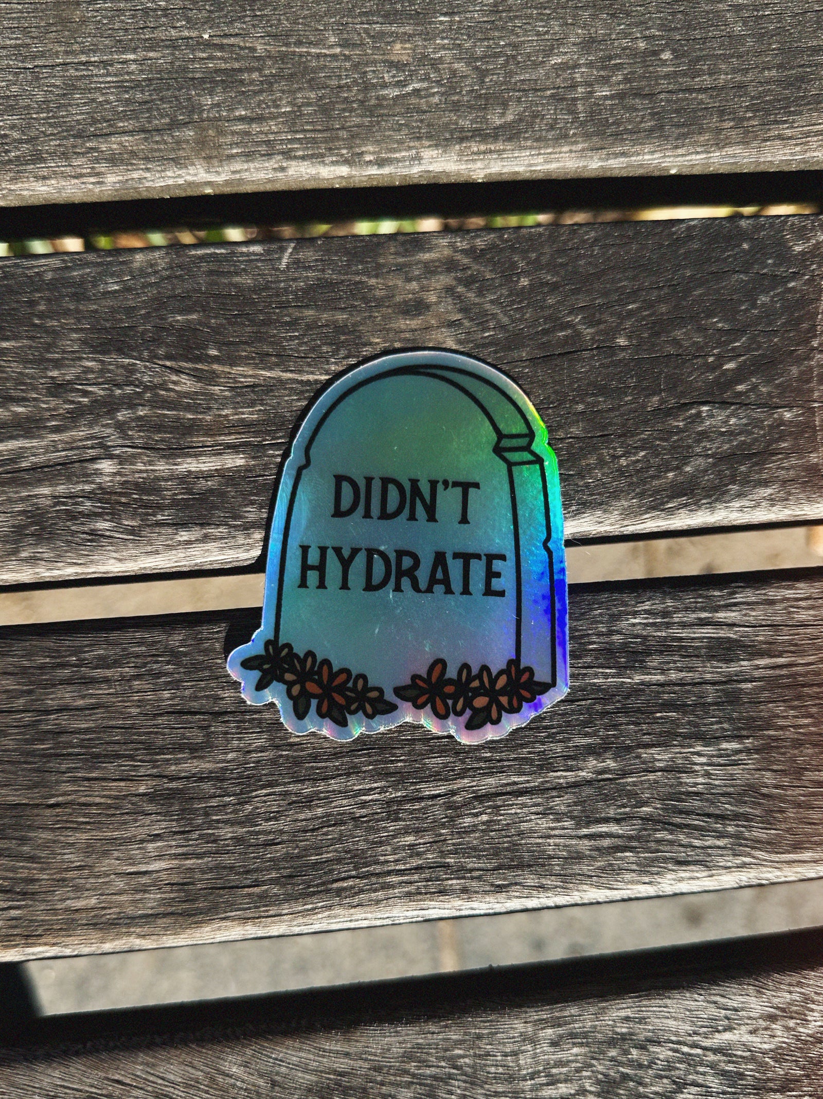 Gradient sticker with 'Didn't Hydrate' text on a wooden surface