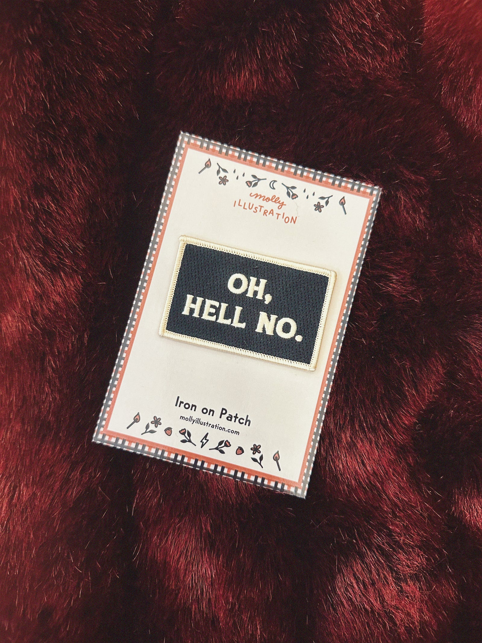 Close-up of a red textured fabric with a patch reading 'OH,HELL NO.'