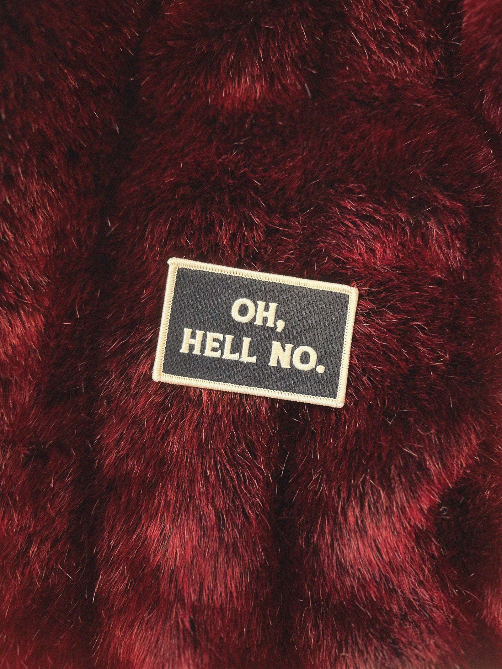 Close-up of a red textured fabric with a patch reading 'OH,HELL NO.'