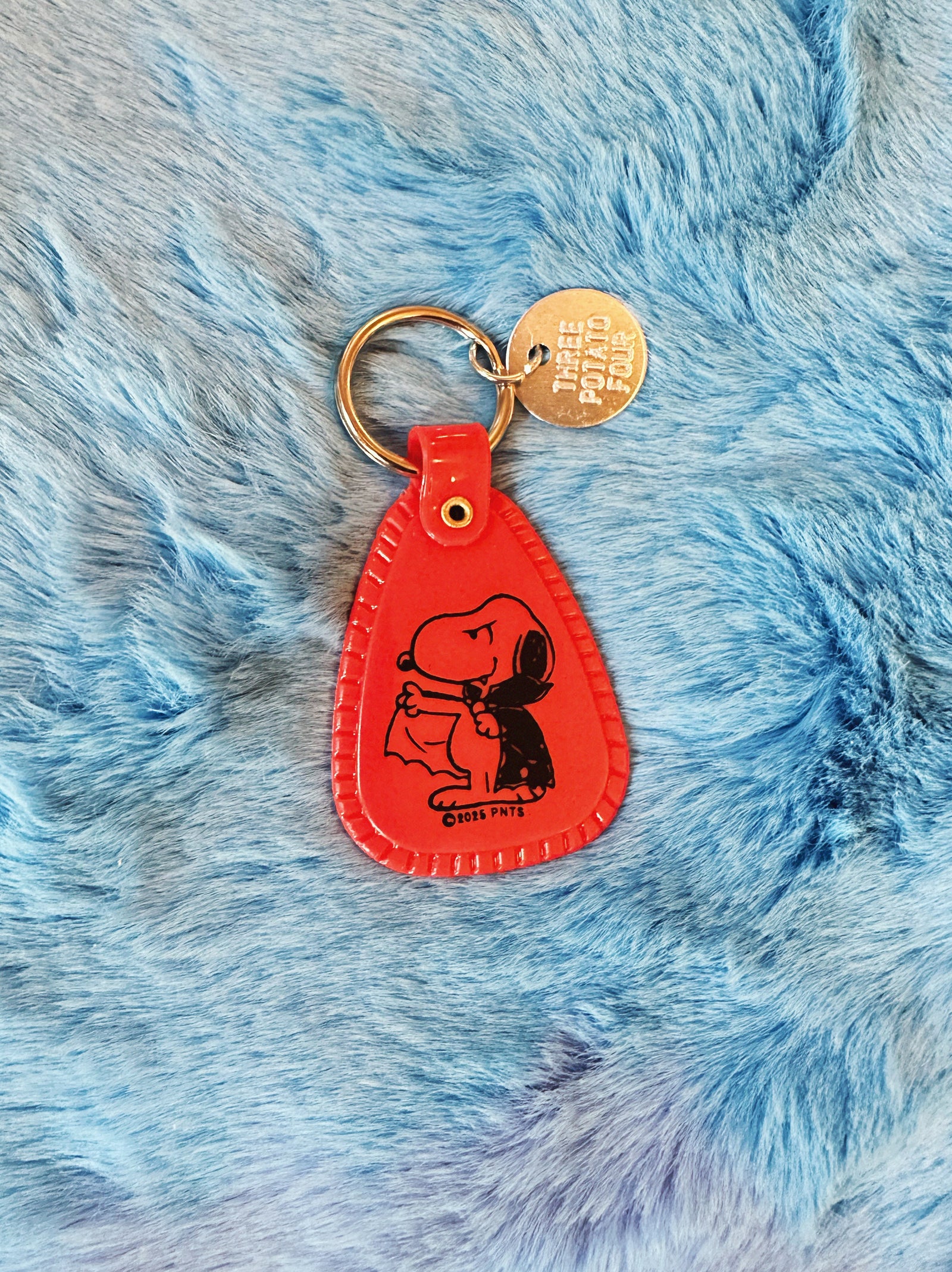 Black and Orange saddle style Halloween Snoopy Vampire Keychain on a fuzzy blue background.