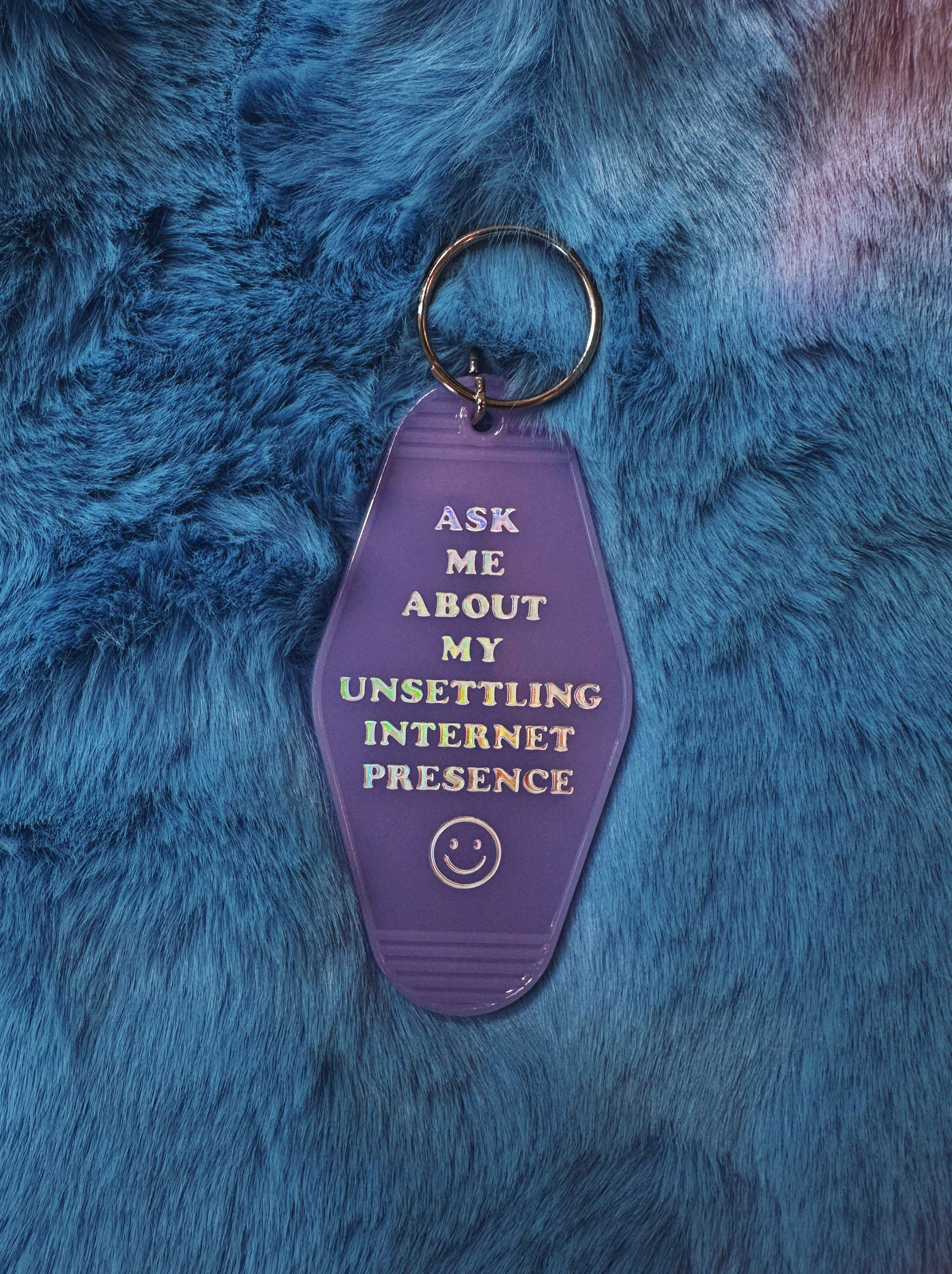 Purple keychain with text on a blue furry background