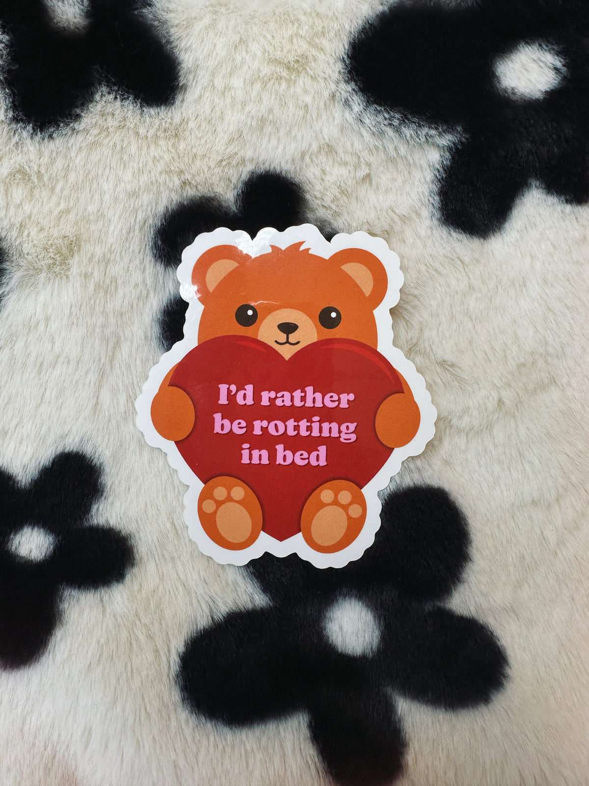 Sticker of a bear holding a heart with text on a fluffy black and white background
