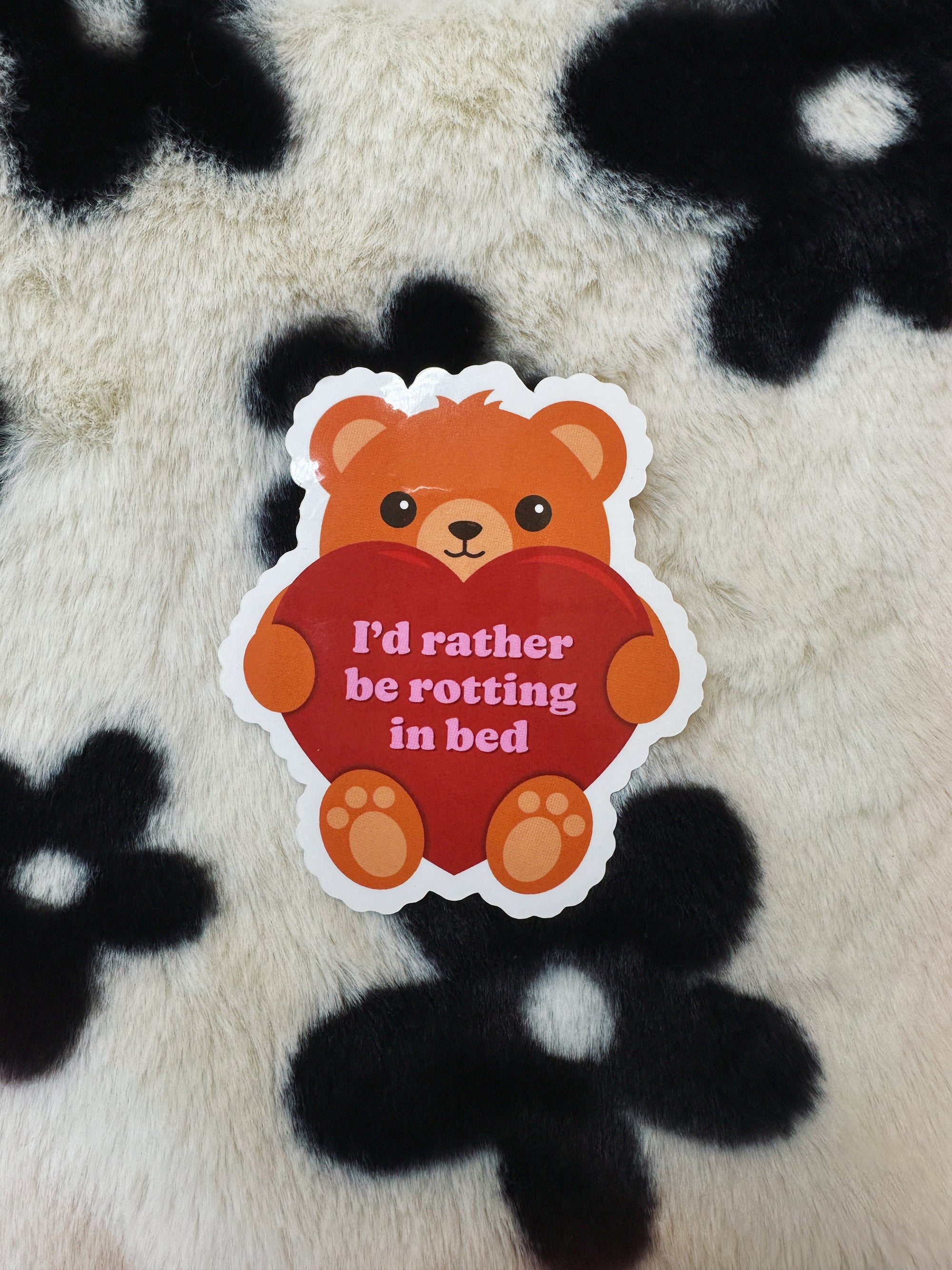 Sticker of a bear holding a heart with text on a fluffy black and white background