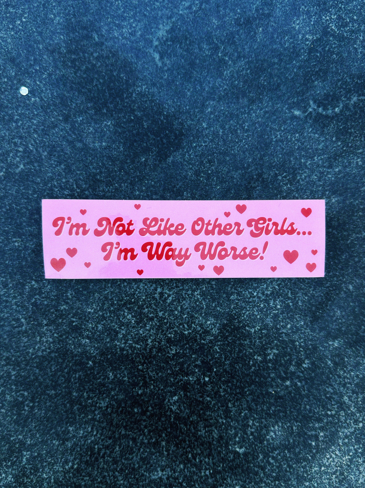 Pink sticker with text &#39;I&#39;m Not Like Other Girls... I&#39;m Way Worse!&#39; on a textured blue background