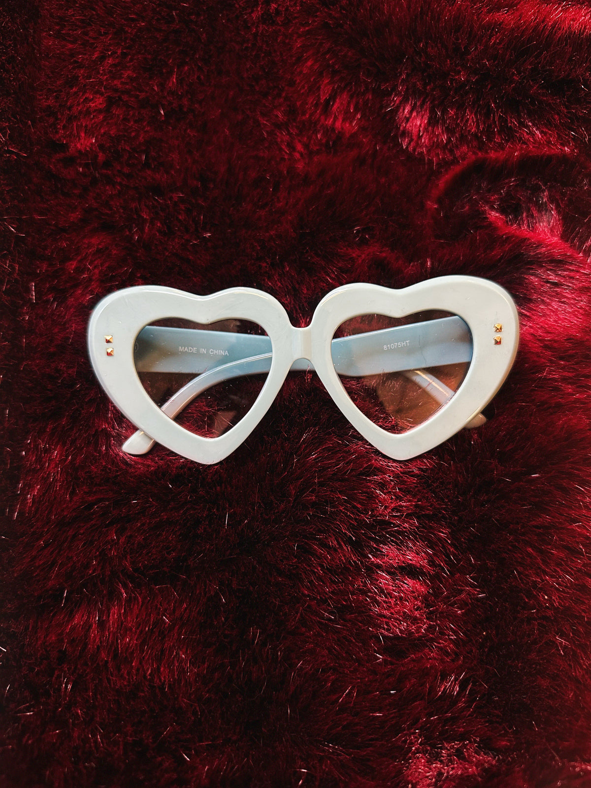 Blue heart-shaped sunglasses on a red textured background