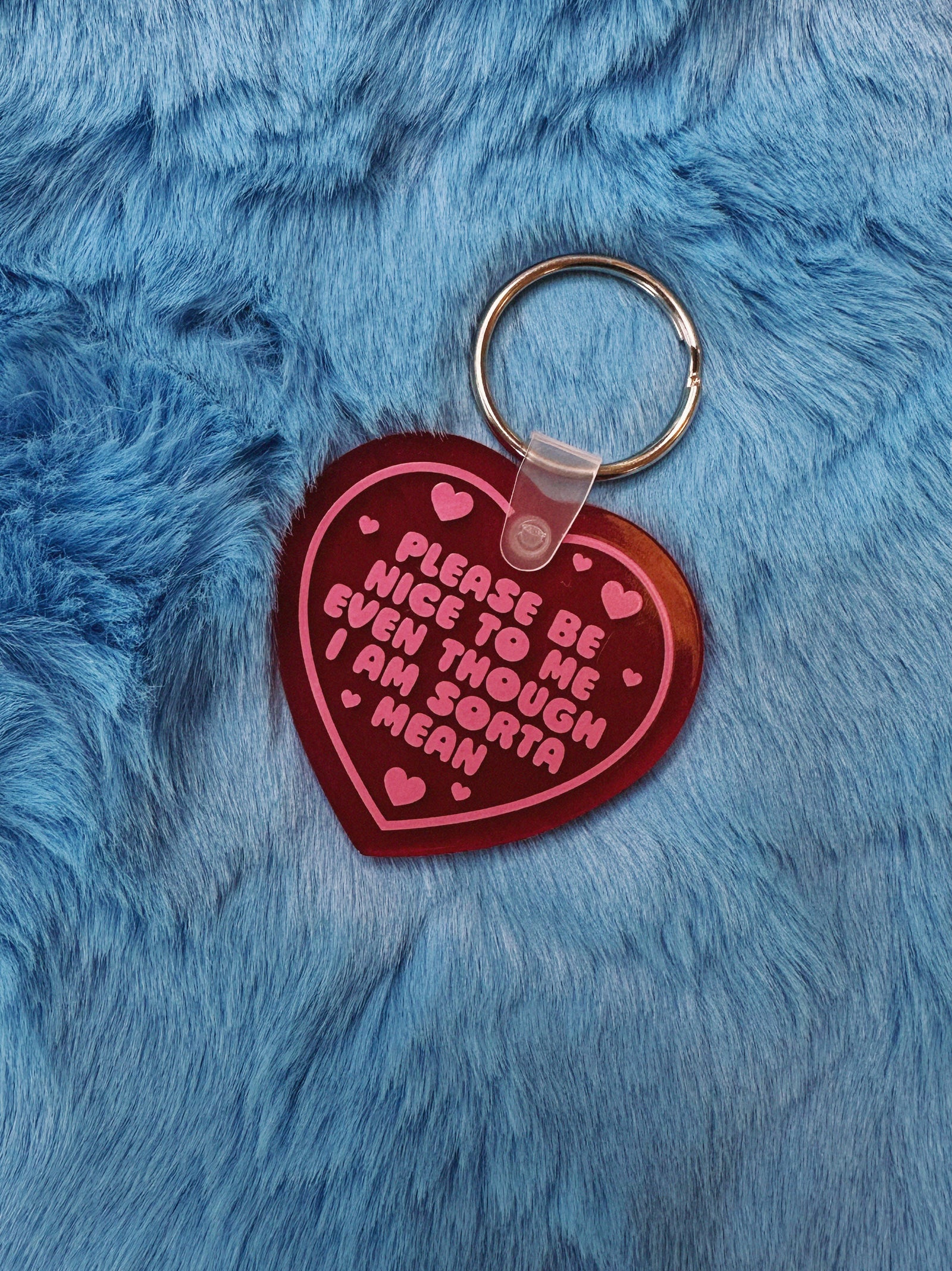 Heart-shaped keychain with pink text on a blue furry background