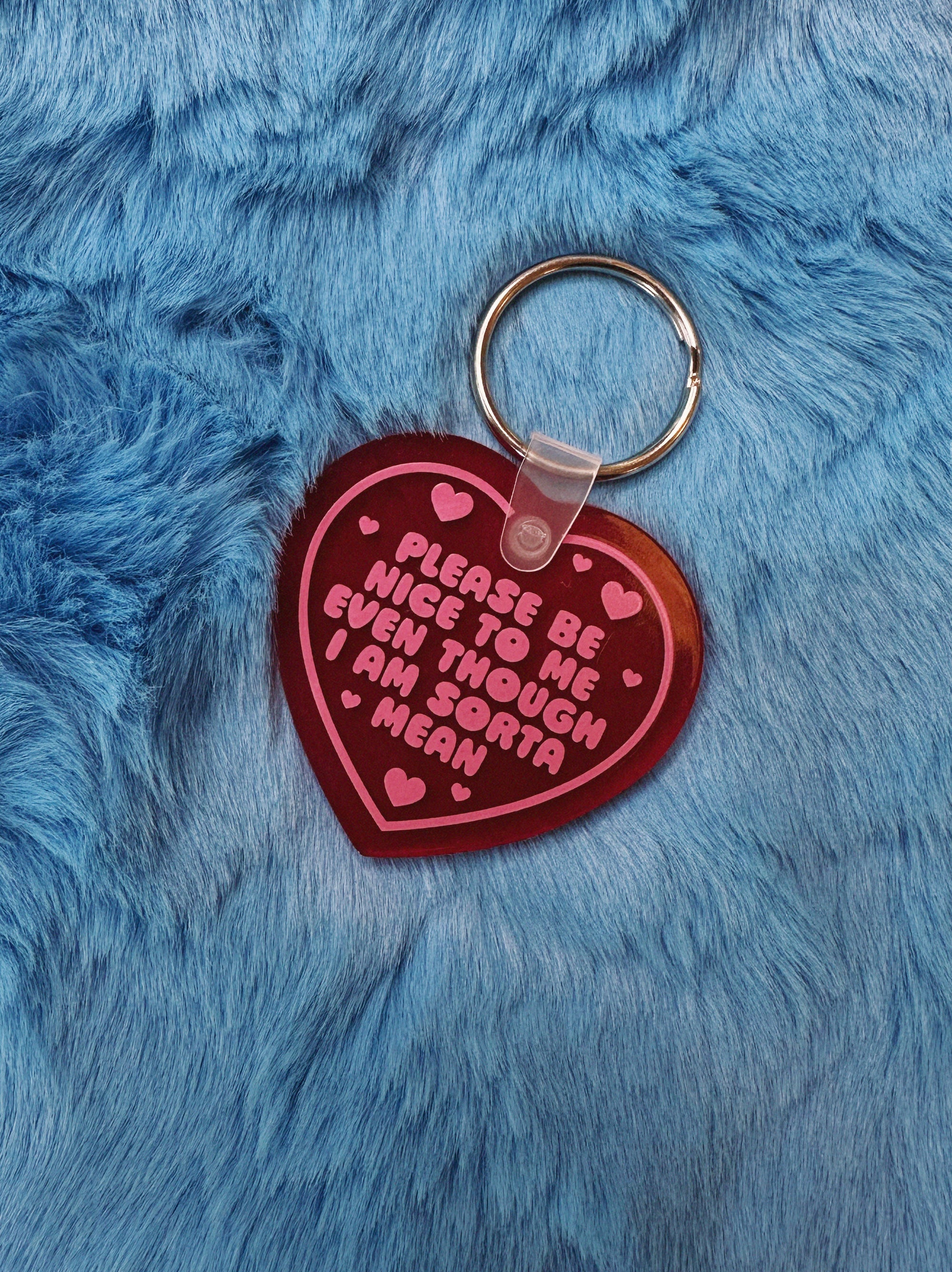 Heart-shaped keychain with pink text on a blue furry background