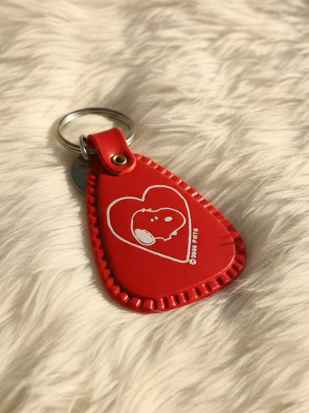 Red saddle style keychain with a white snoopy in a heart graphic on a white fur background