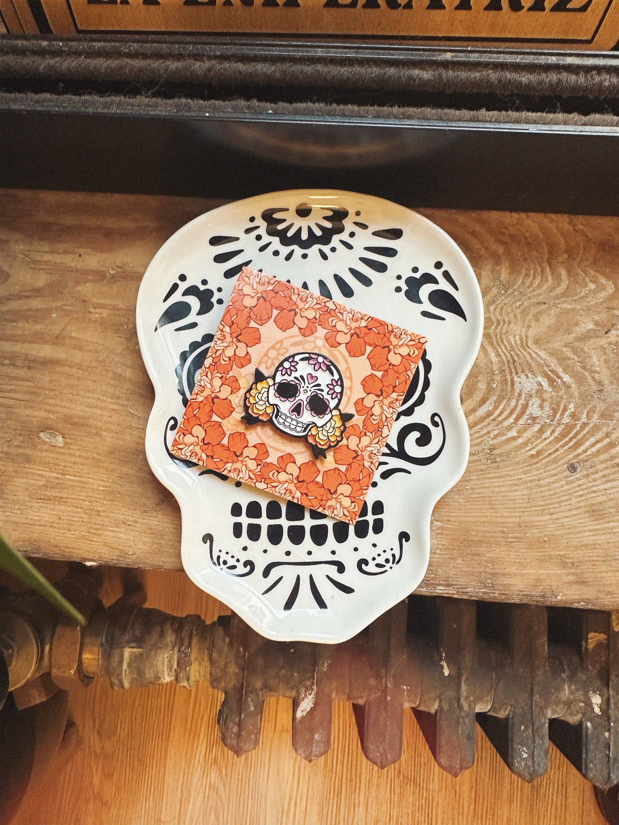 Decorative skull with floral patterns and a central skull design on a wooden surface.