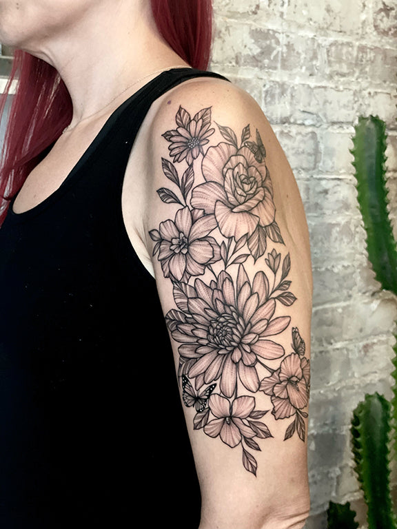 Delicate, fine line black and gray floral upper arm tattoo by Janice Danger