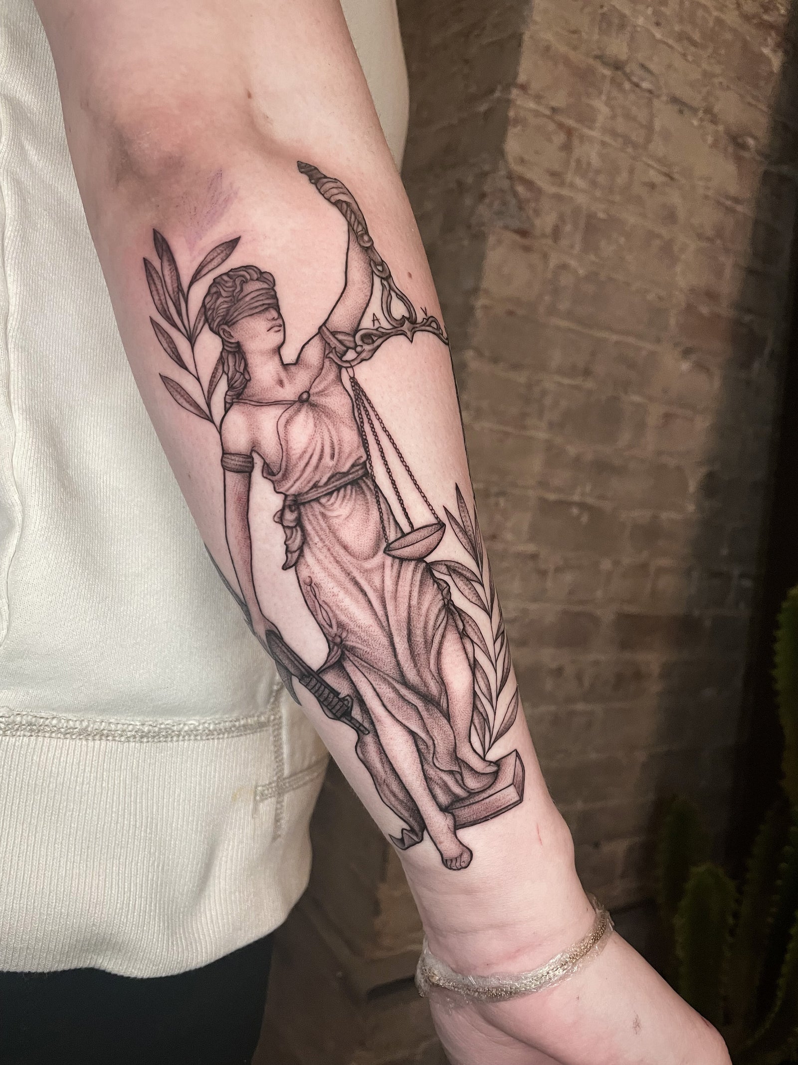 Black and gray Lady Justice with laurels forearm tattoo by Janice Danger