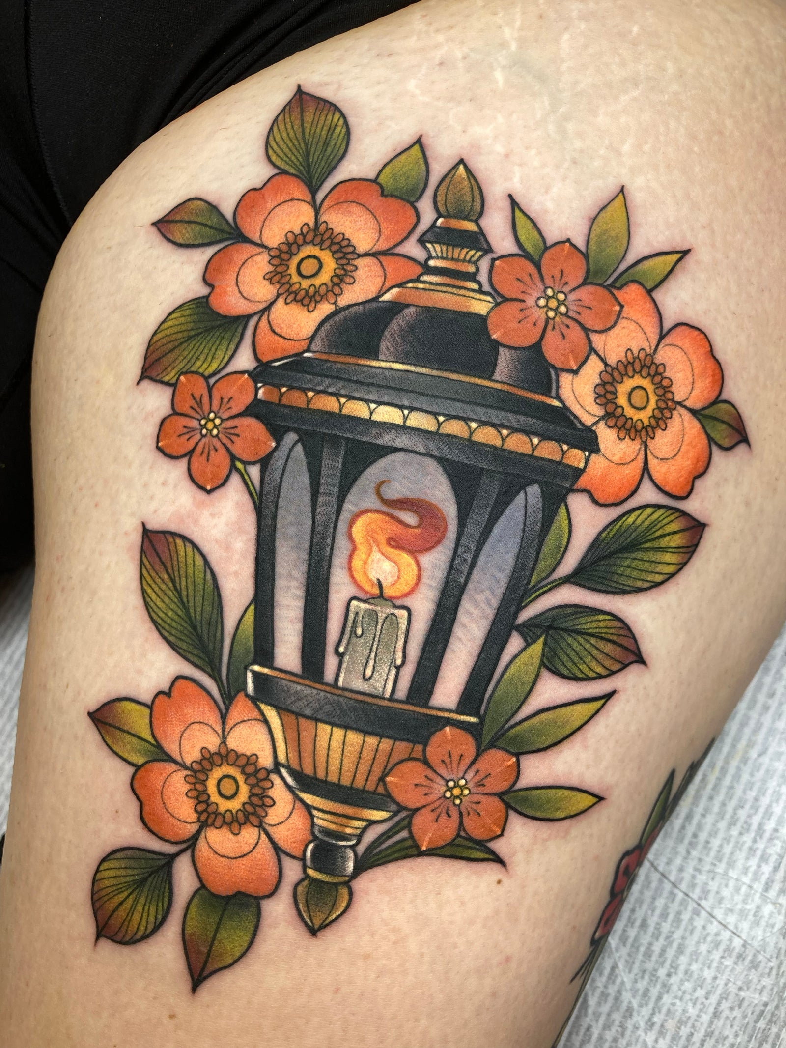 Neo-traditional lantern tattoo with orange flowers and green foliage. 