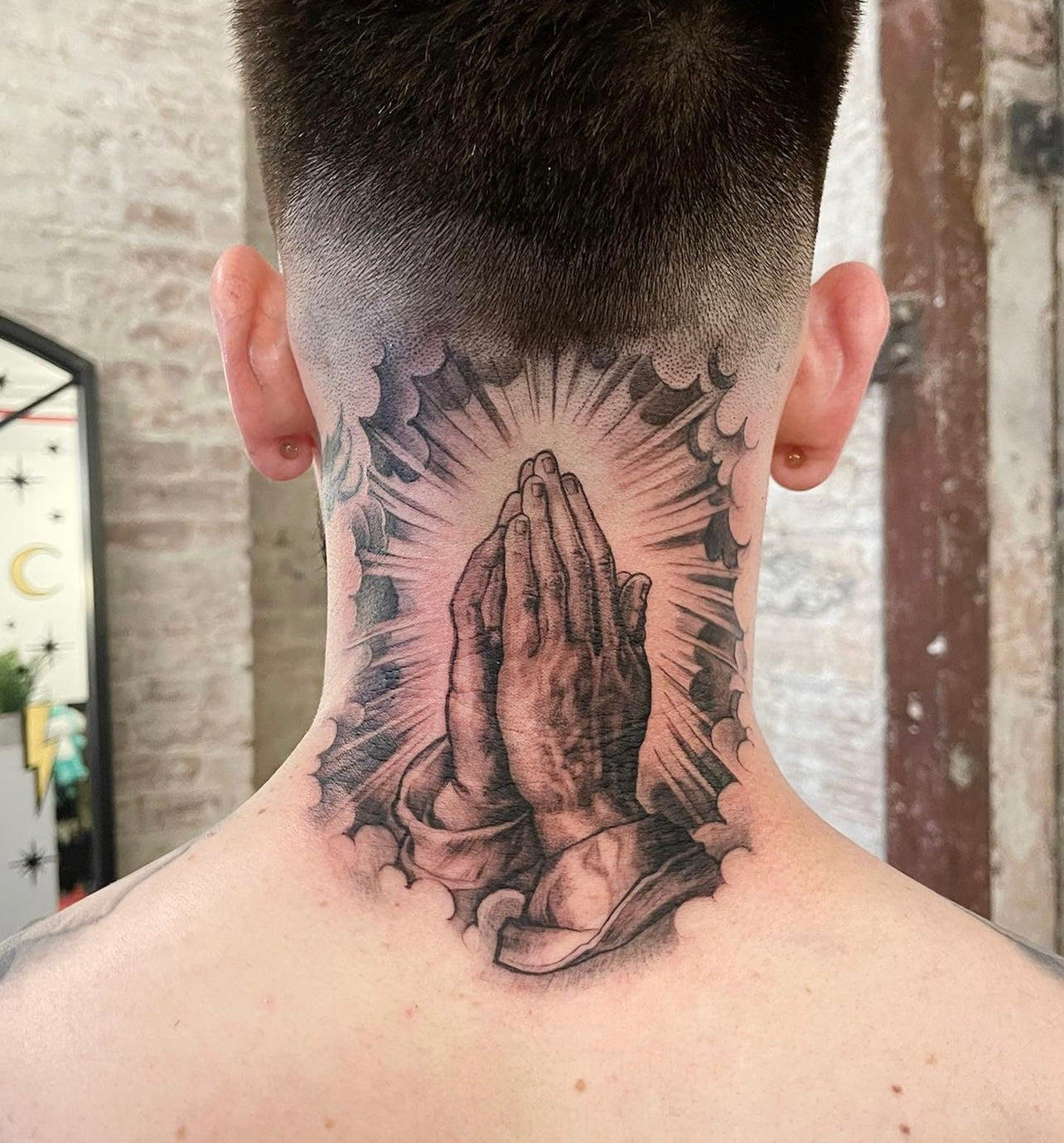 Praying Hands black and gray tattoo on the back of the neck by Elvia Guadian at Grit N Glory in New York City