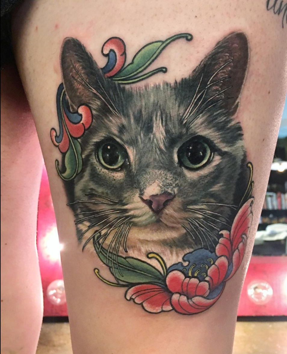 color realism cat portrait thigh tattoo featuring illustrative flowers by Megan Massacre