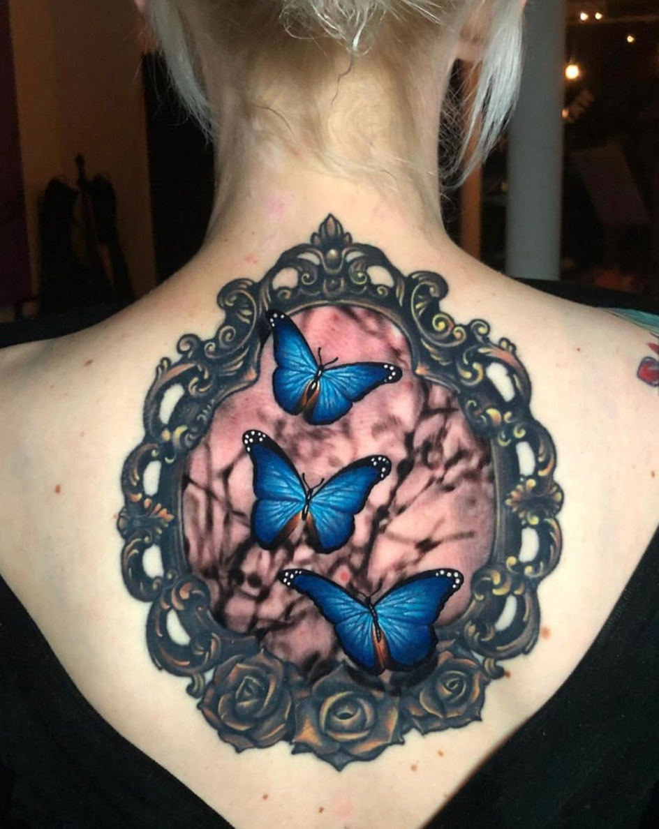 Blue, realistic butterflies in ornate frame upper back tattoo by Megan Massacre