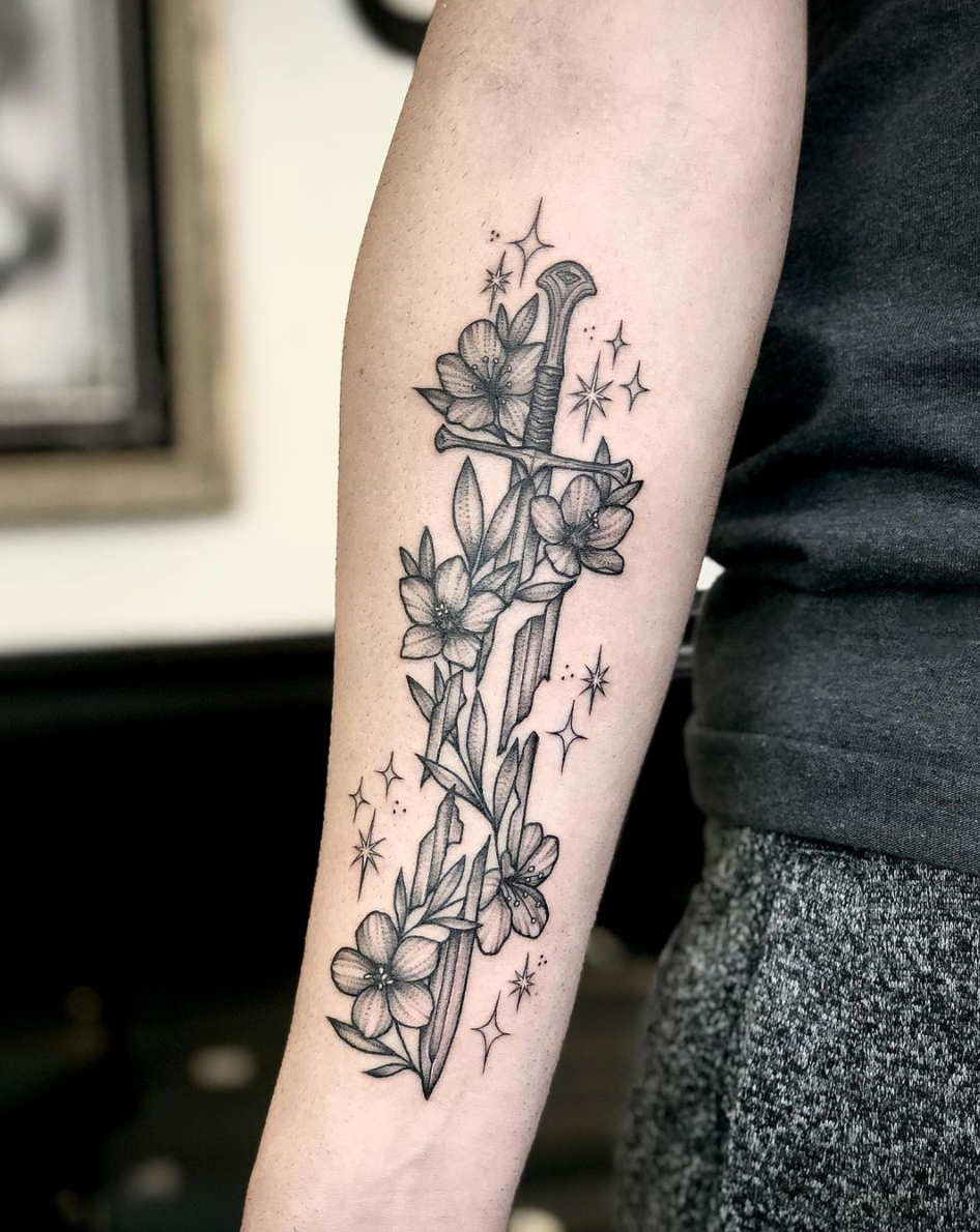 Illustrative blackwork delicate Lord of the Rings sword and floral arm tattoo by Janice Danger