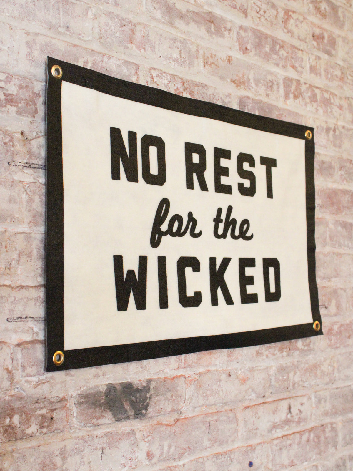 off white and black banner reads "No Rest for the Wicked" with 4 gold grommets