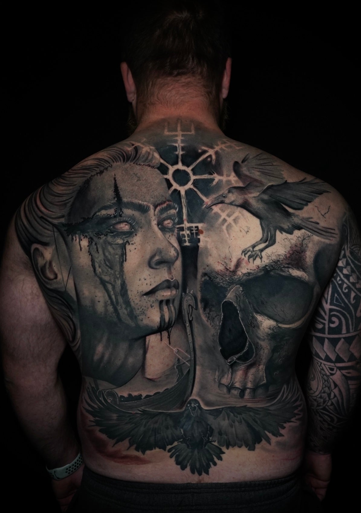 Black and gray back piece tattoo made by Joanna Gacek featuring a skull, rune, and ravens.  