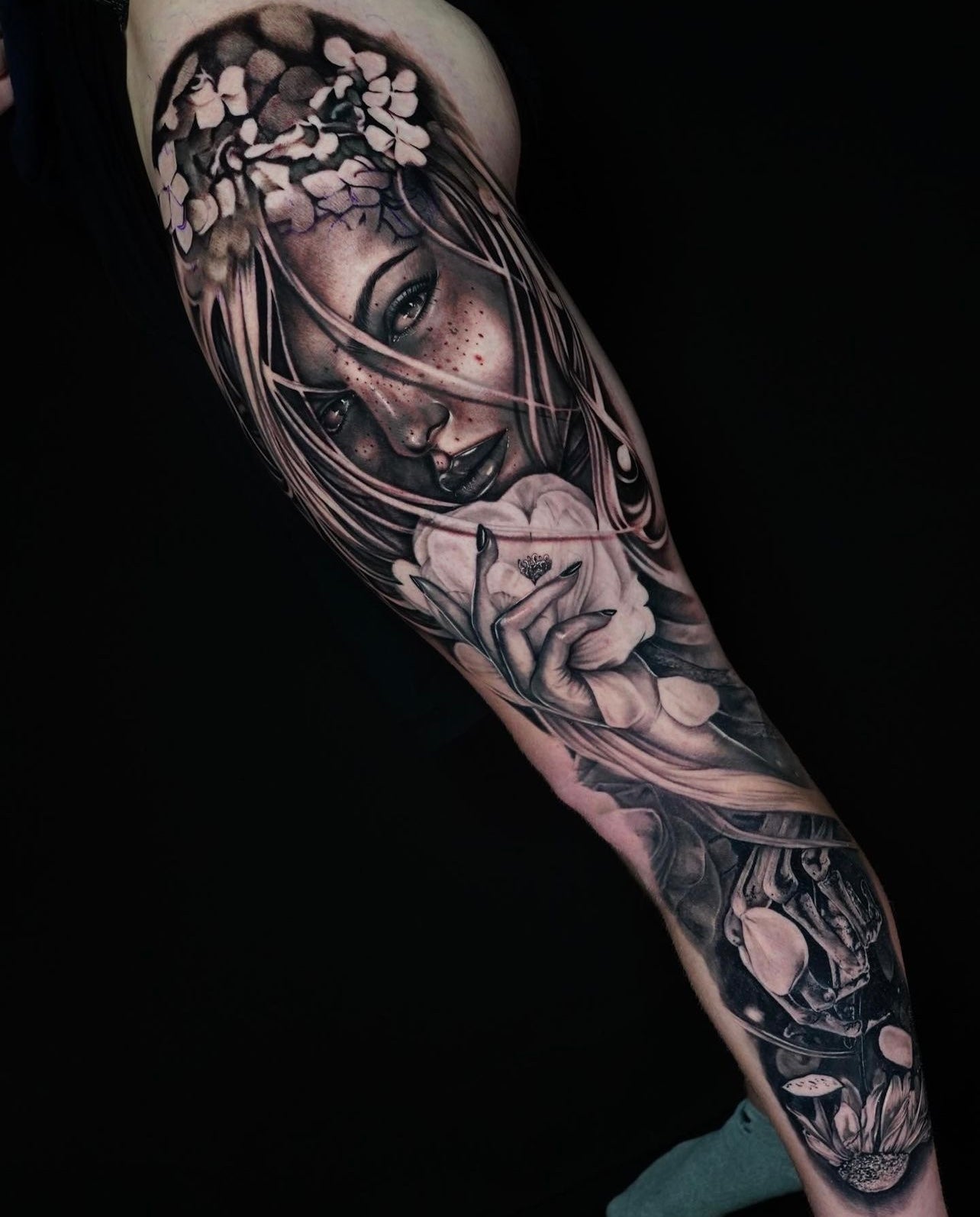 Black and gray realism large scale arm tattoo featuring a woman and flowers made by Joanna Gacek