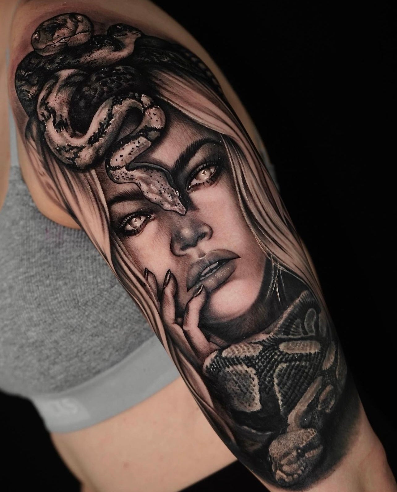 Black and gray realism woman with a snake upper arm tattoo by Joanna Gacek