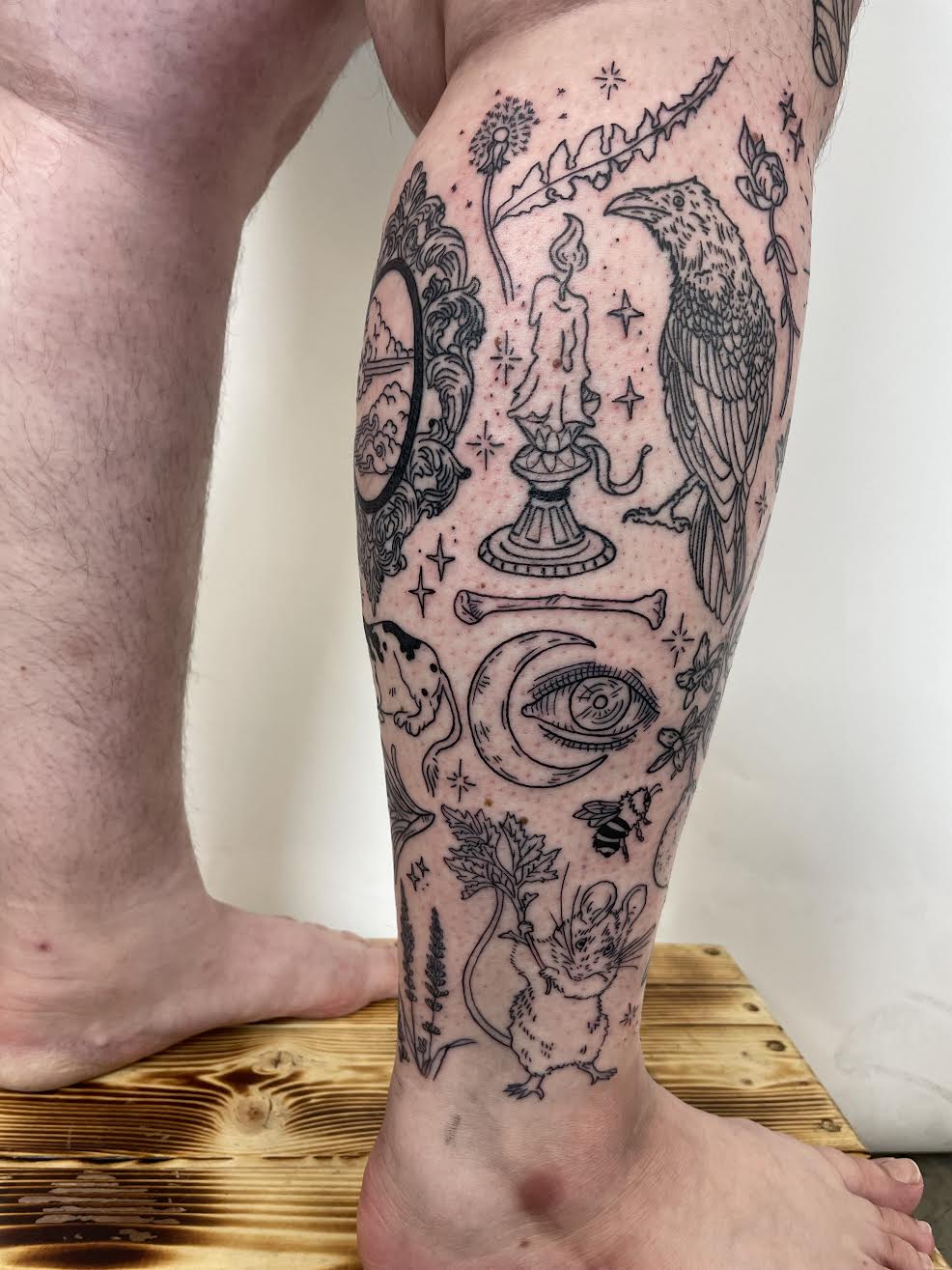 blackwork patchwork leg tattoo with crescent moon, eye, mouse, candle by Mehak Basu