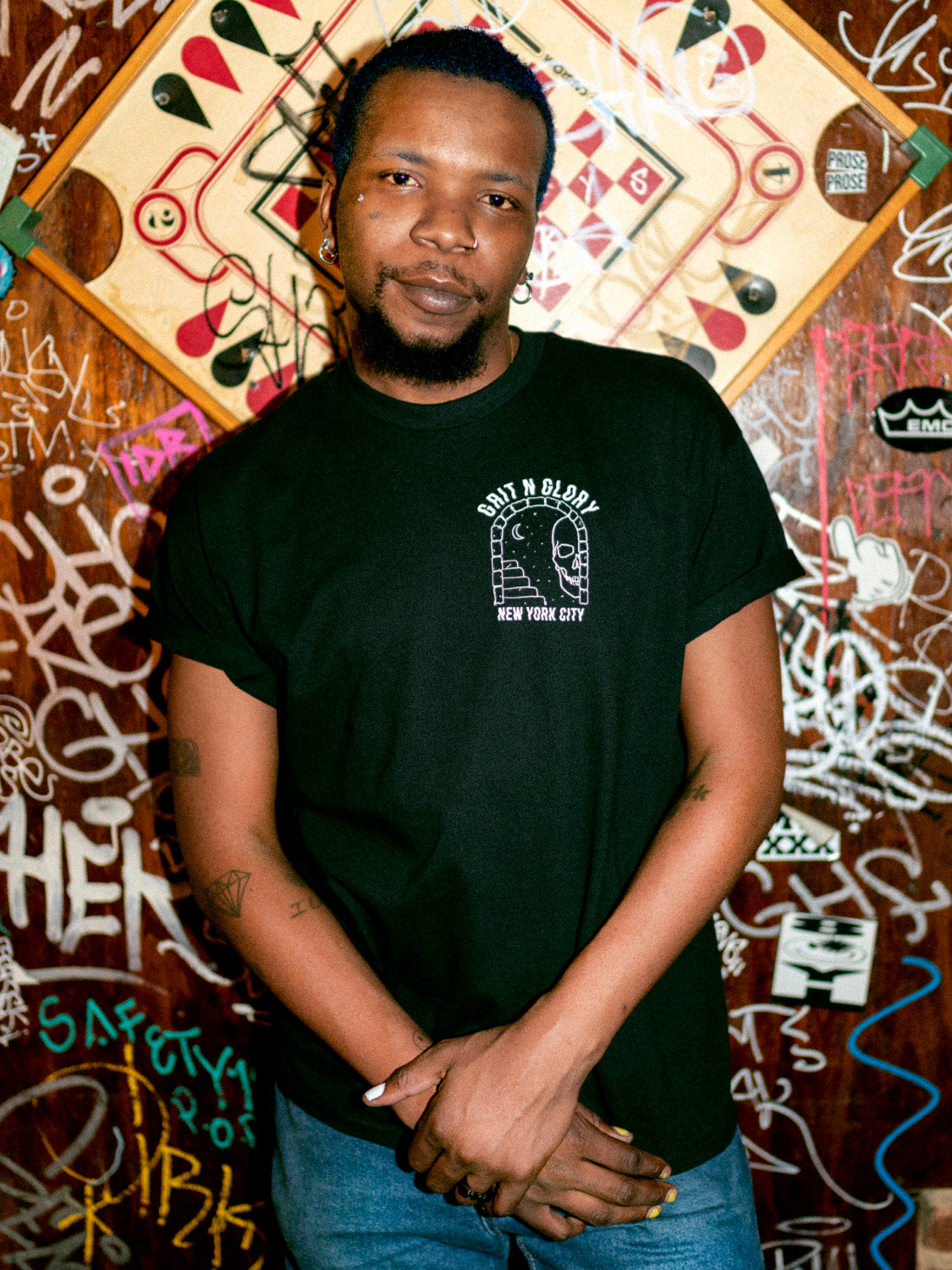 A person wearing a black graphic tee with the text 'IF LOST PLEASE RETURN TO GRIT N GLORY' on the back.