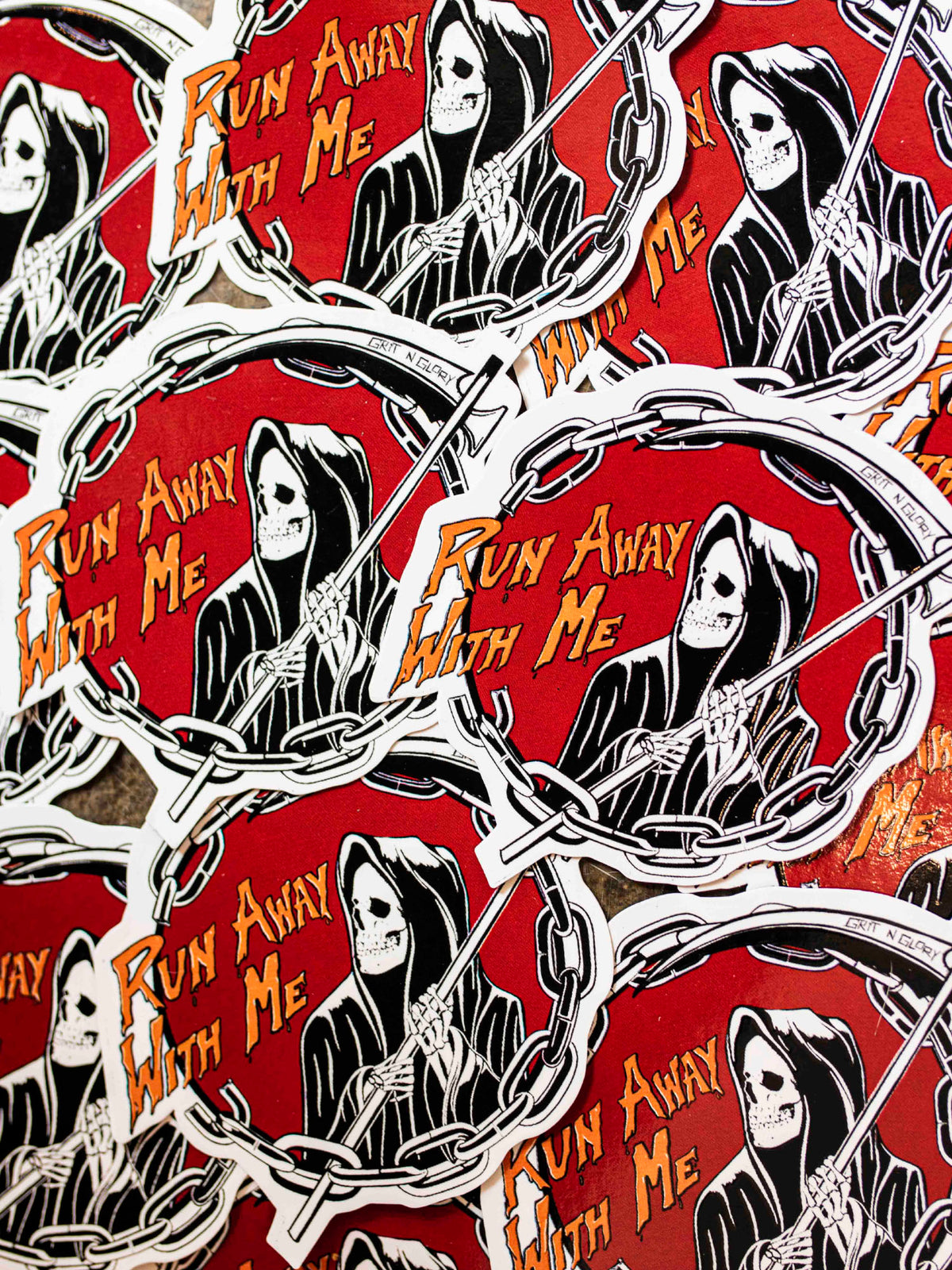 Die cut vinyl stickers with a black and white reaper design in a red circle
