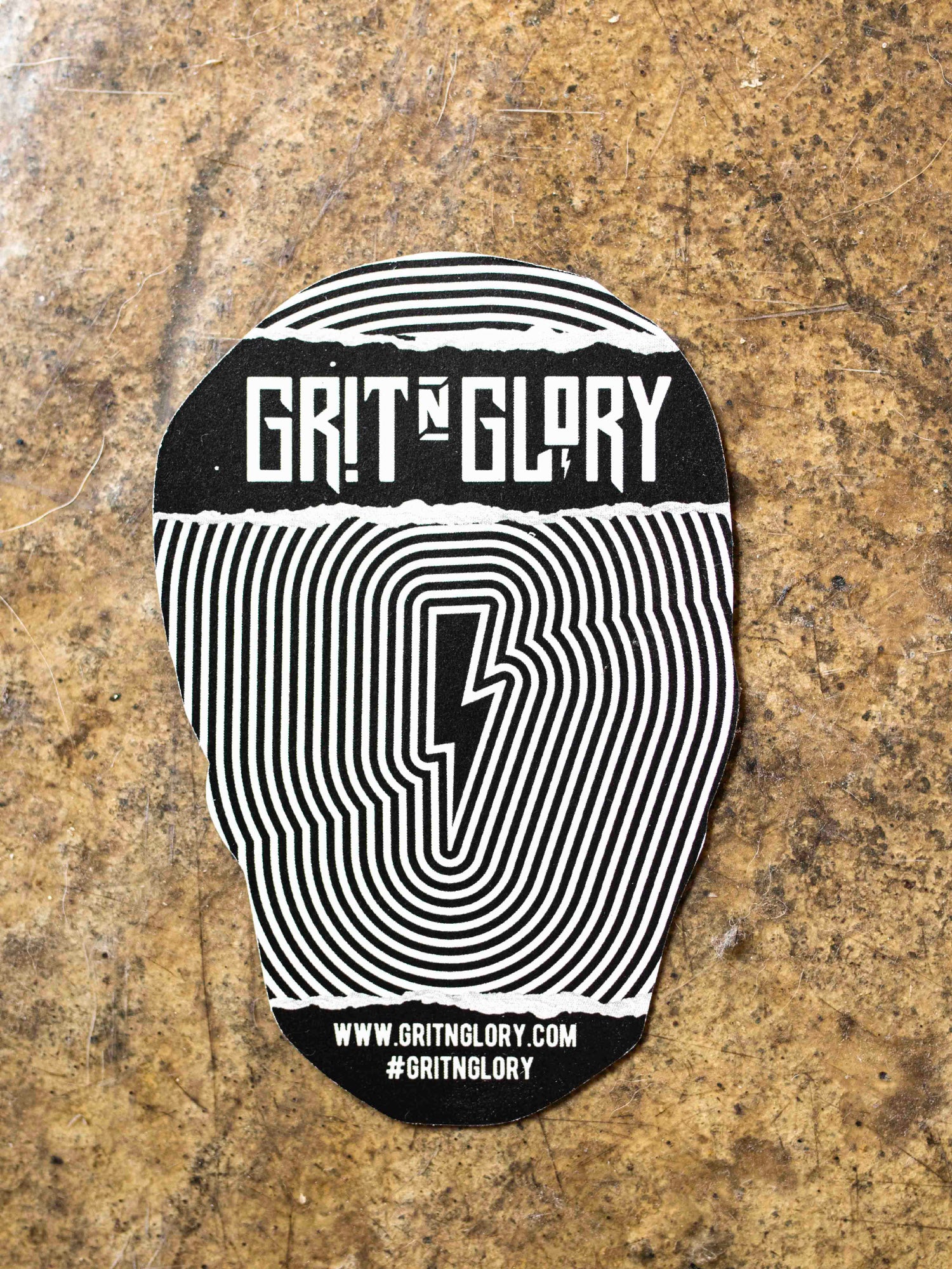 A black, white, and gold die-cut sticker of a skull with an eye the top forehead area.