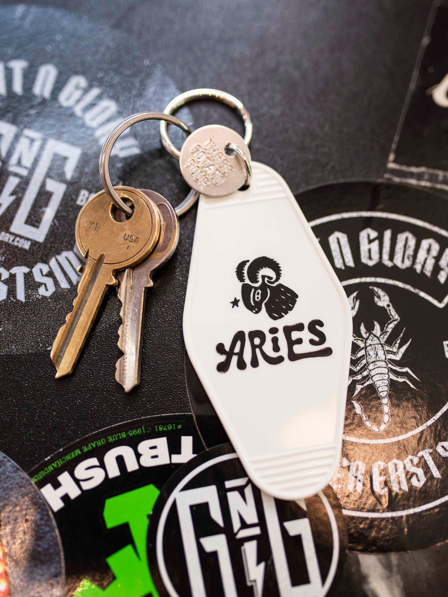 White retro motel style astrology keychain with two keys on a black solid background. 