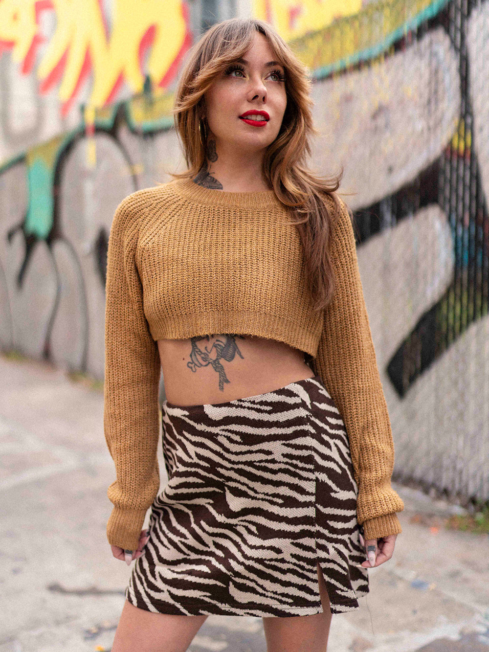 Megan Massacre wearing a knit zebra print mini skirt with a cropped sweater. 