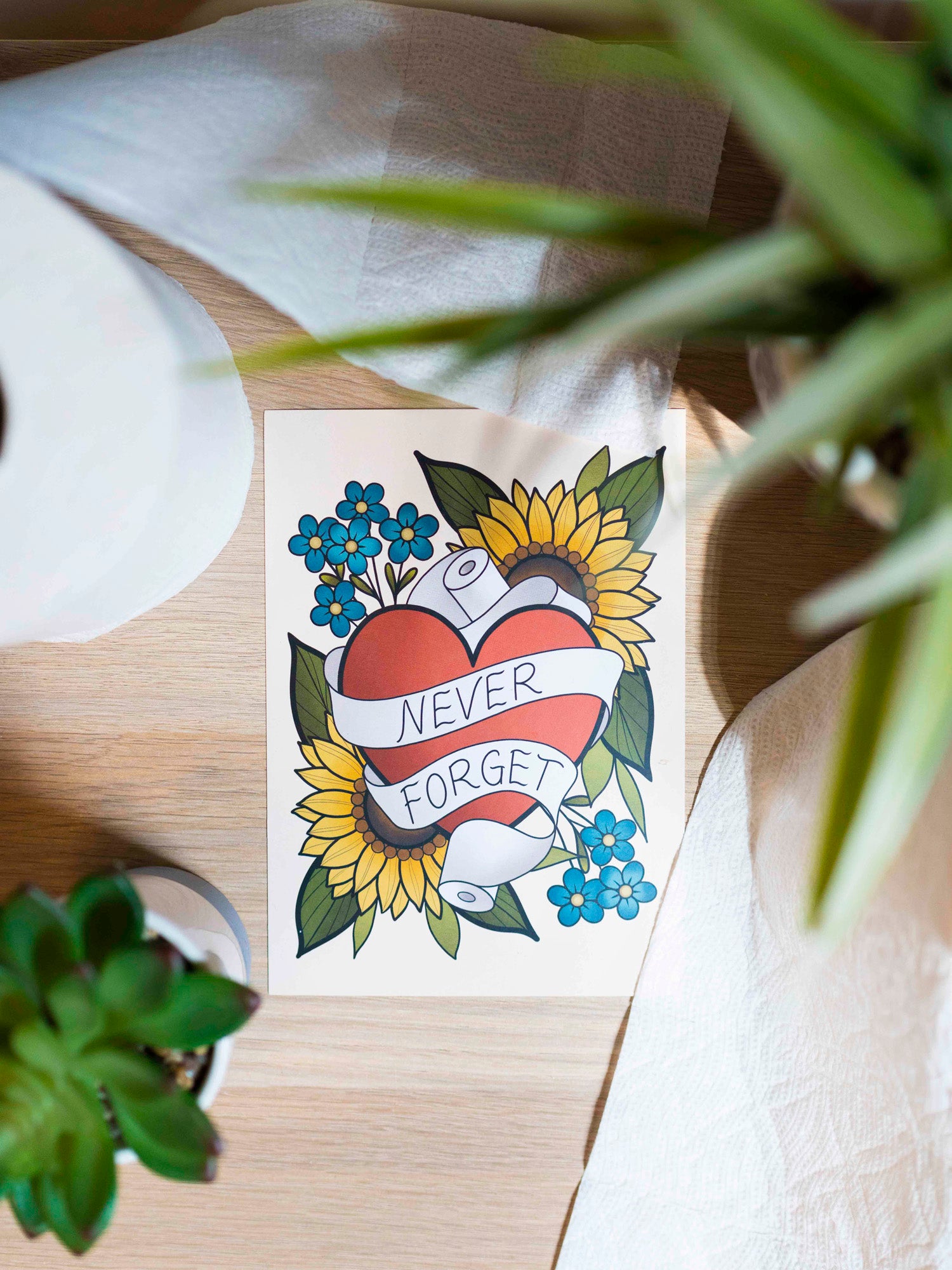 Small funny art print reads "never forget" in a traditional tattoo style leaning against toilet paper rolls.