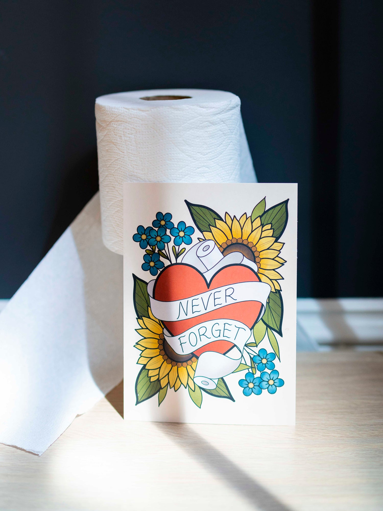 Small funny art print reads "never forget" in a traditional tattoo style amongst toilet paper rolls.