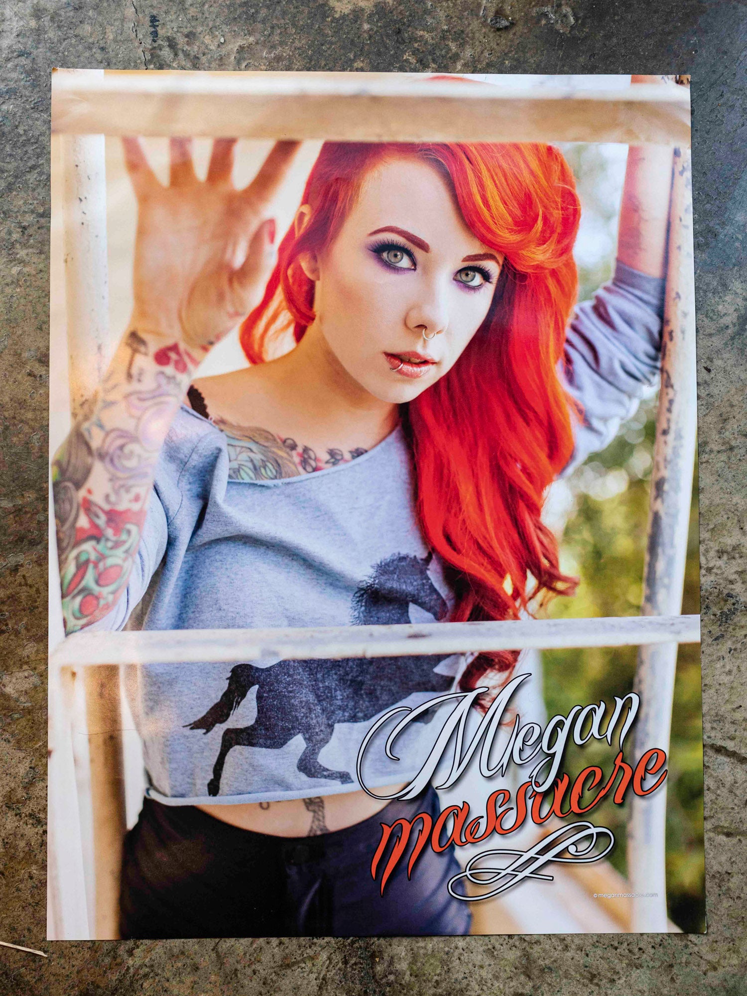 Megan Massacre holding a signed copy of her Unicorn Poster featuring Megan Massacre with red hair and a unicorn crop top. 