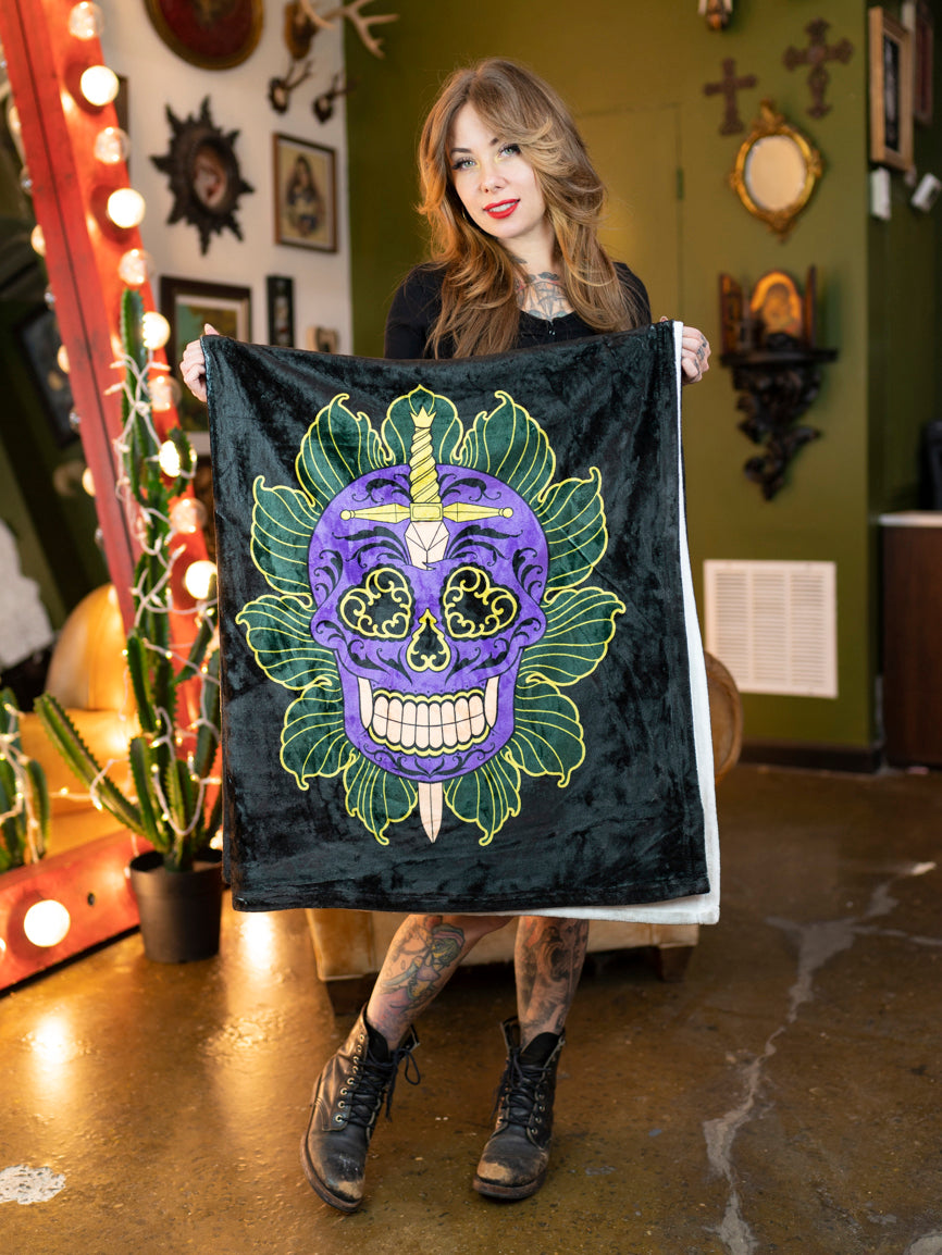 Megan Massacre with her black and white plush blanket with a colorful sugar skull design.