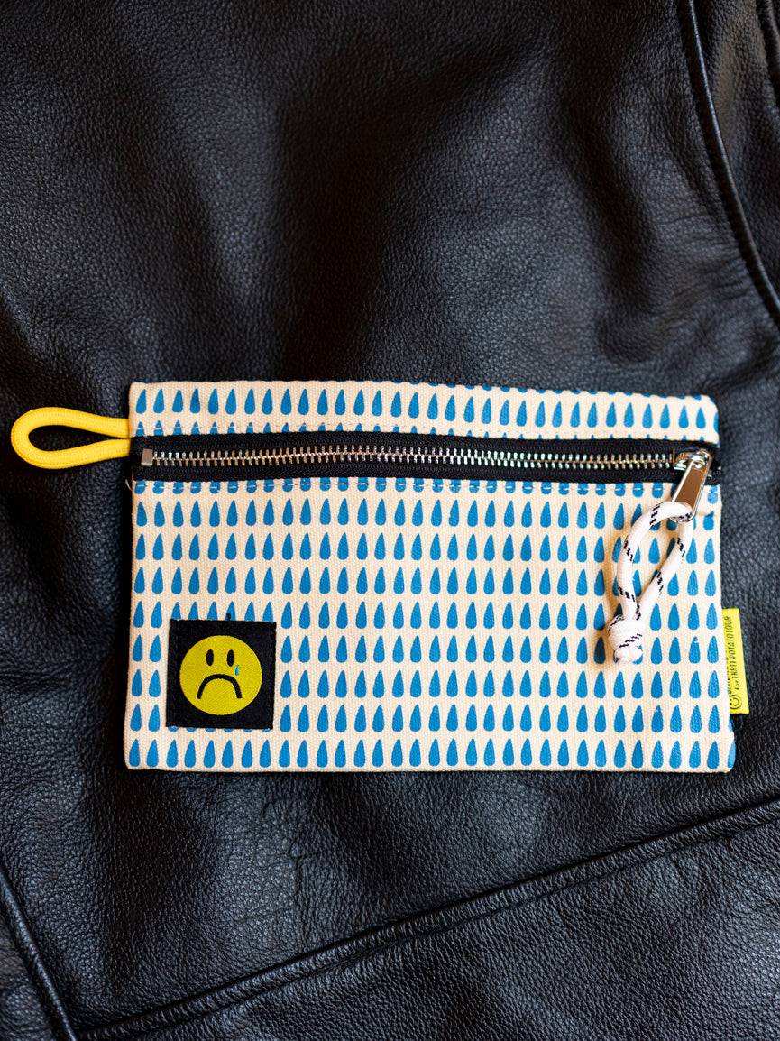 A Sad Face Zip Pouch with a blue and white tear drop pattern, a yellow carrying loop, and a yellow and black zipper.