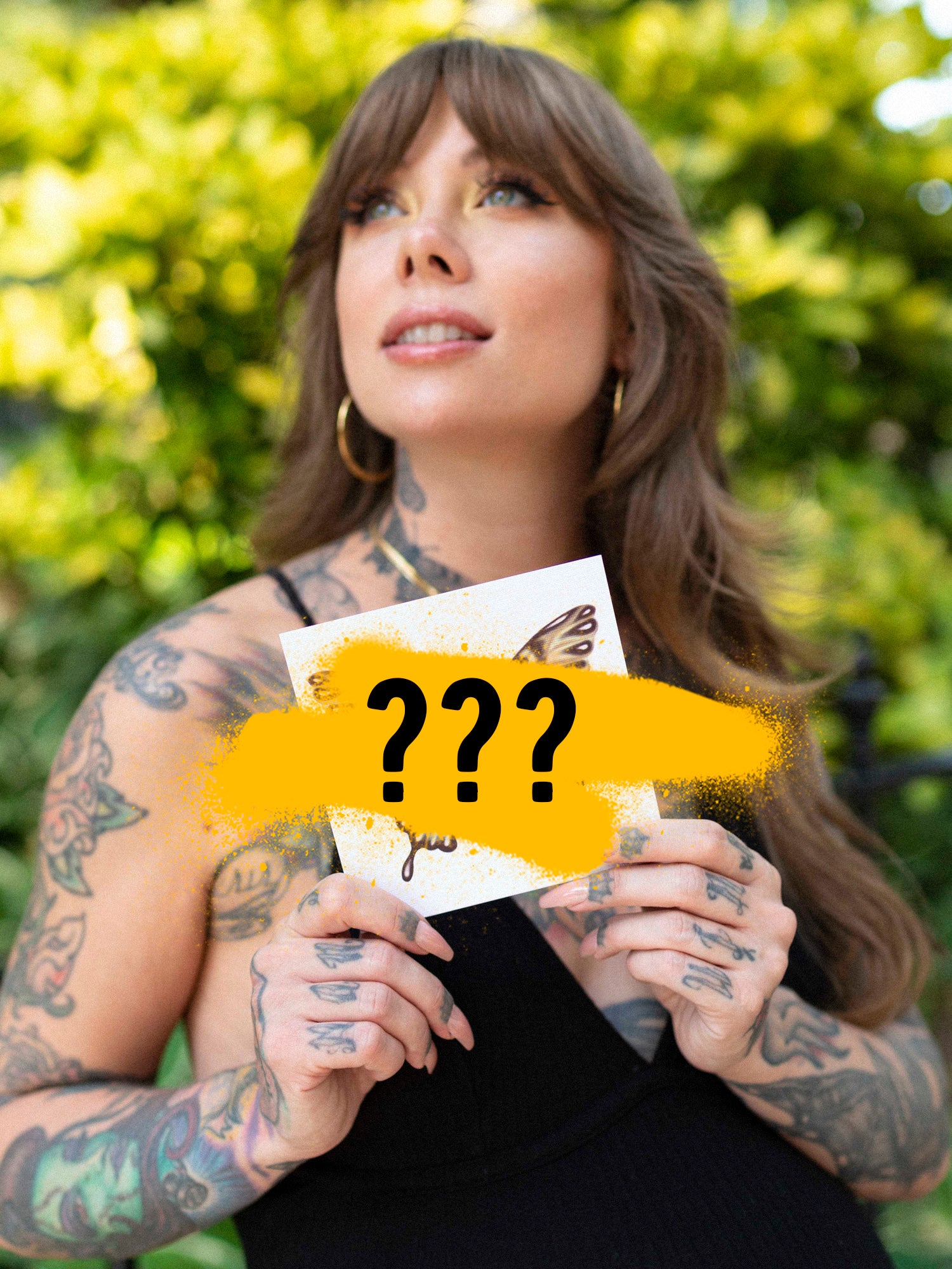 A person holding a mystery print with yellow and black design elements, partially covering the image with their hands.