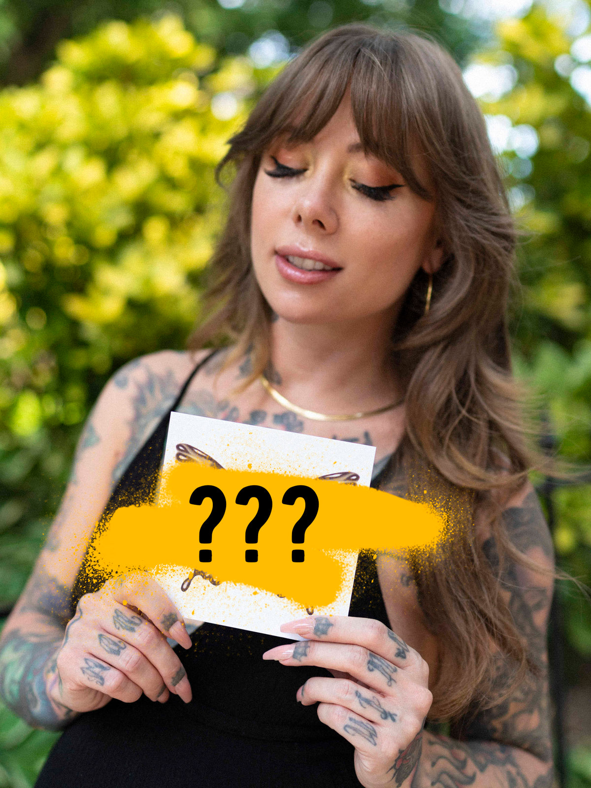 Megan Massacre holding a mystery print with yellow and black design elements, partially covering the image with their hands.