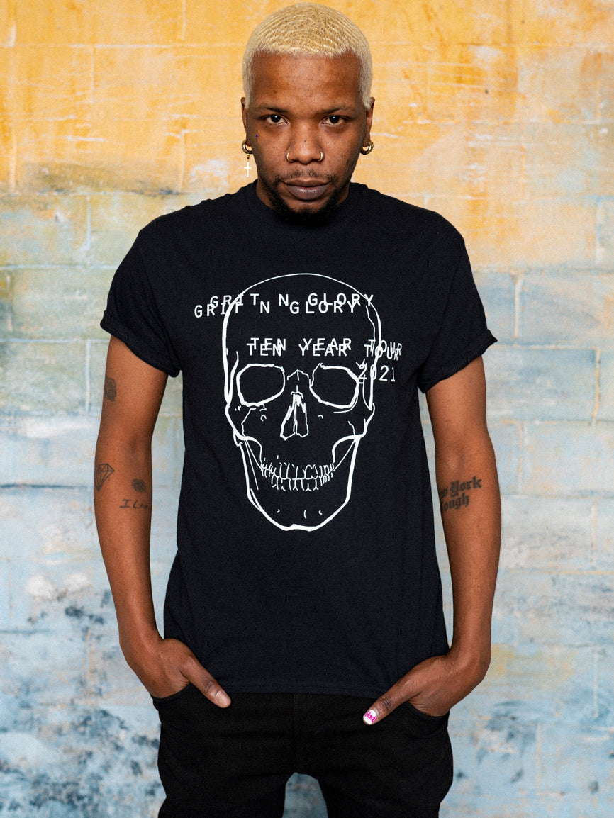 A person wearing a black graphic t-shirt with a white text and skull design on it.