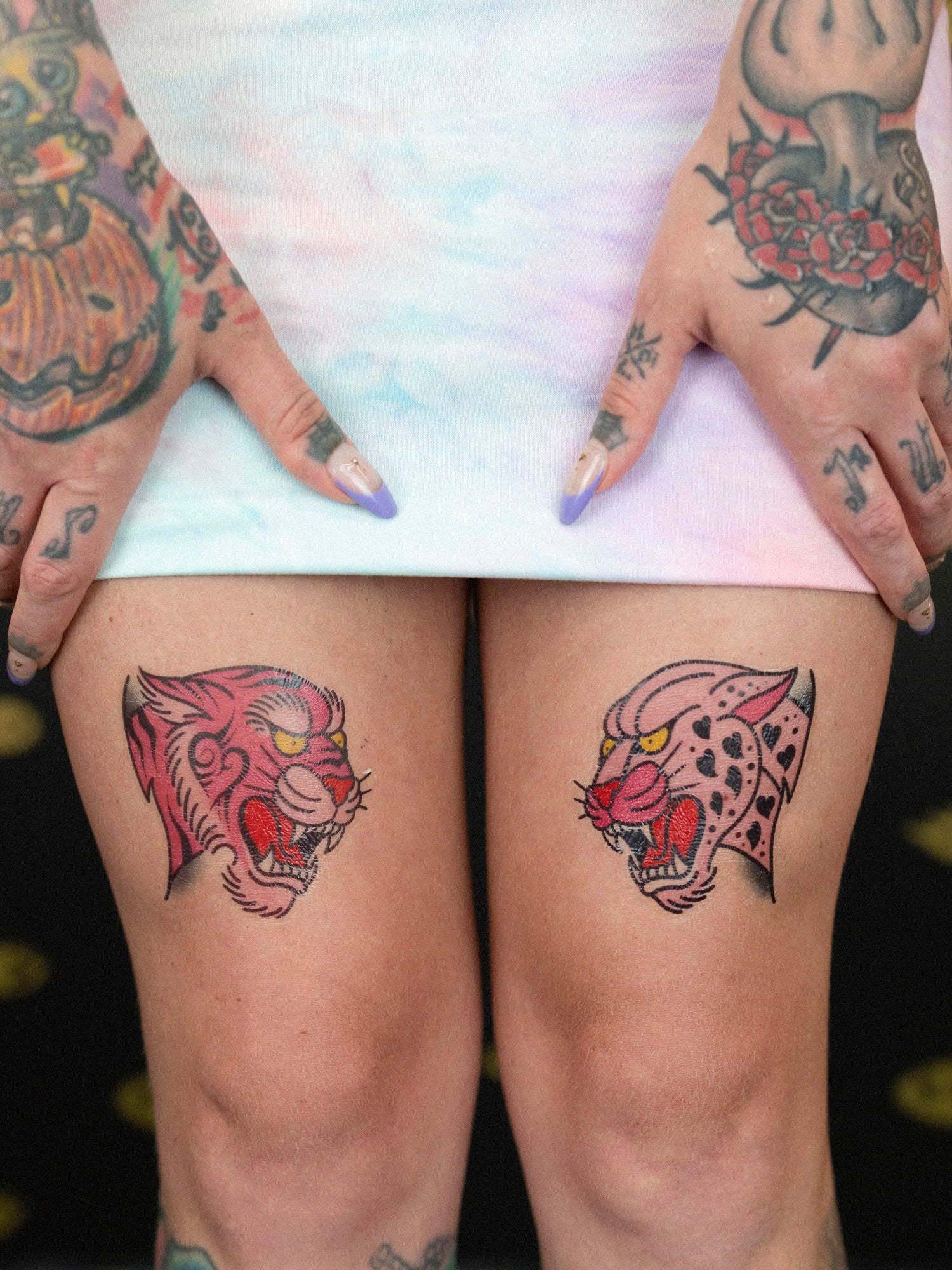 Two pink cat temporary tattoos with packaging among potted plants. 