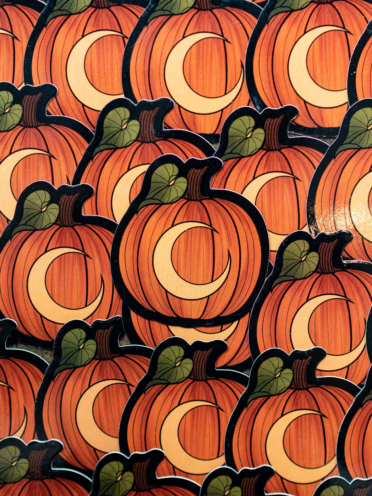 A collection of orange pumpkin stickers with a moon illustration, arranged in a pattern.