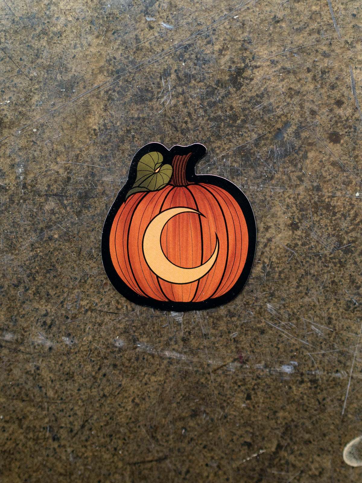 A pumpkin die cut vinyl sticker with crescent moon detail by Charlotte Timmons