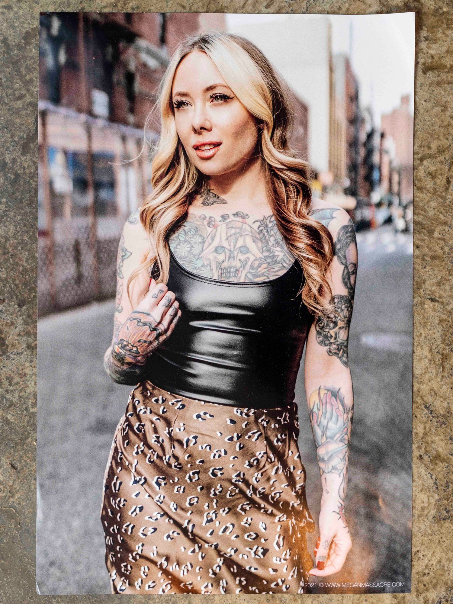 Poster of tattoo artist Megan Massacre with blonde hair with black top and chetah skirt photographed in the lower east side nyc. 