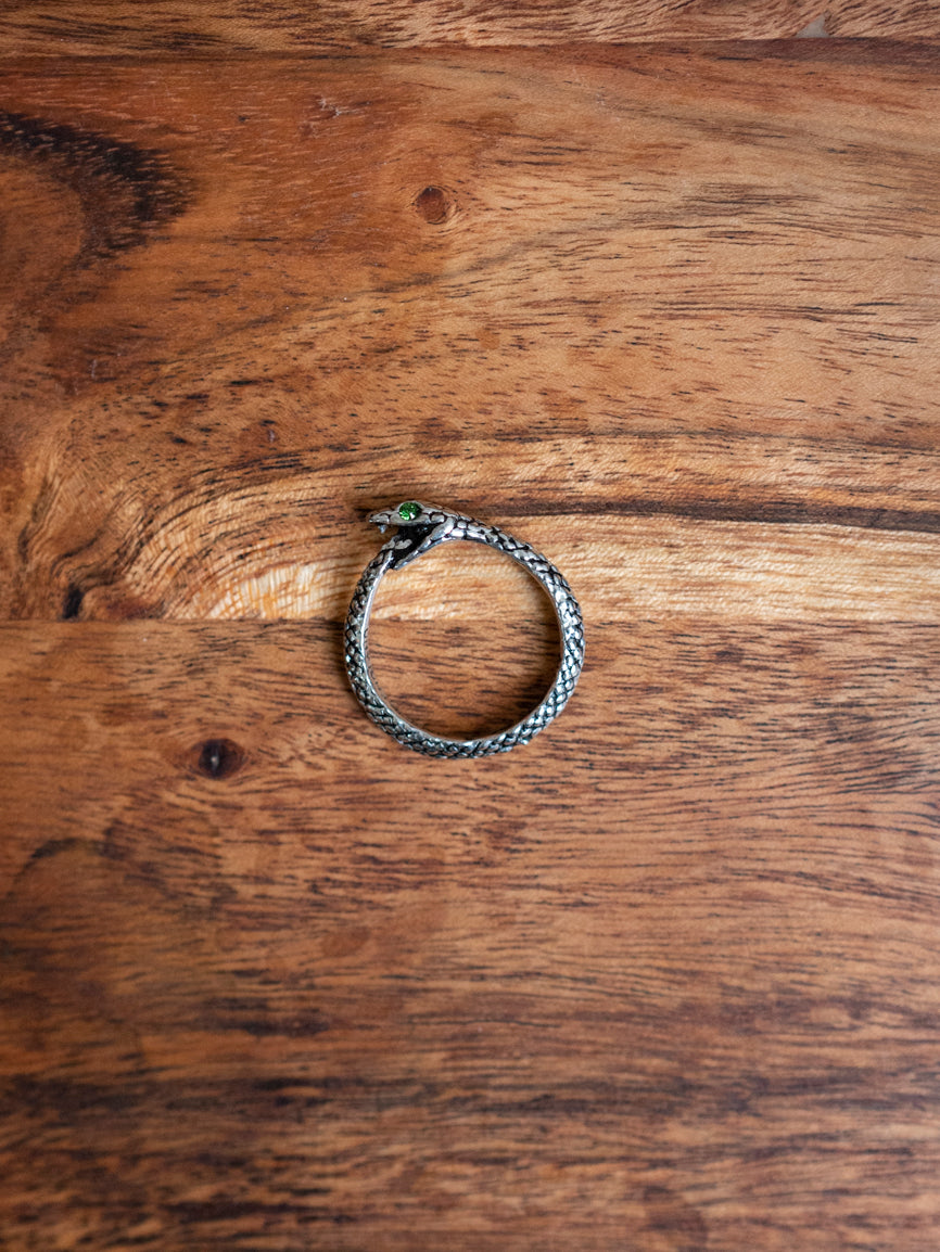 snake ring with green eye details on a wooden surface.